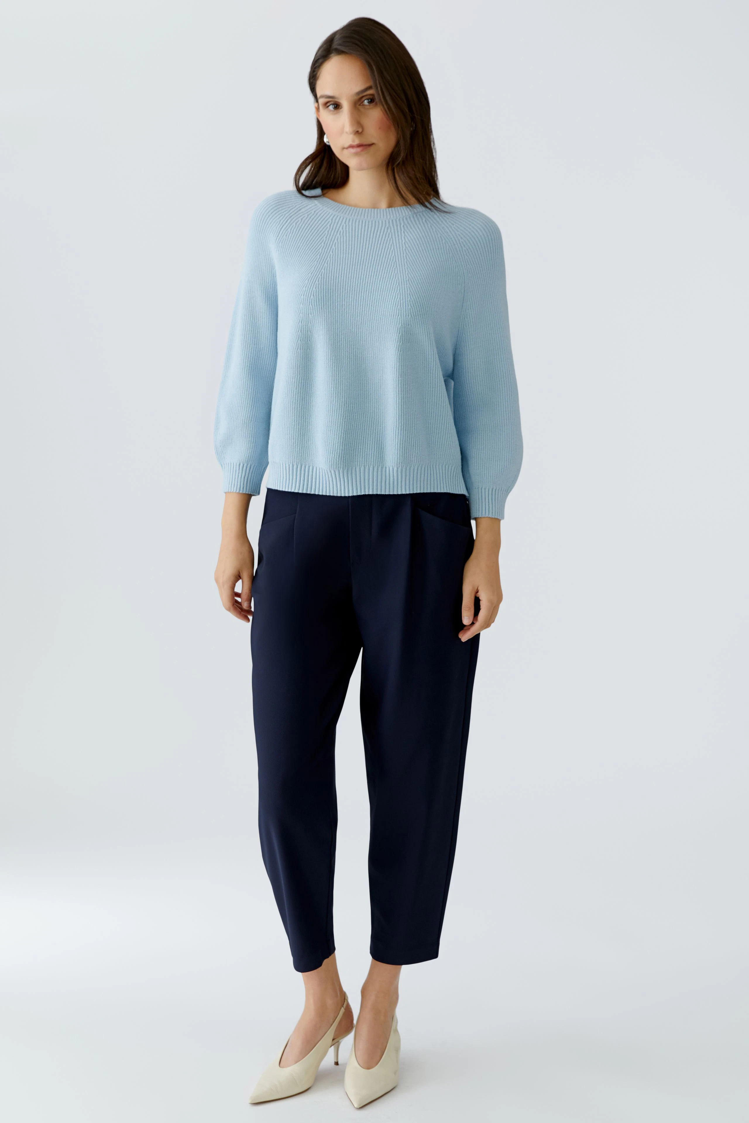 Casual women's pullover: Woman in a light blue pullover with balloon sleeves and relaxed fit pants.