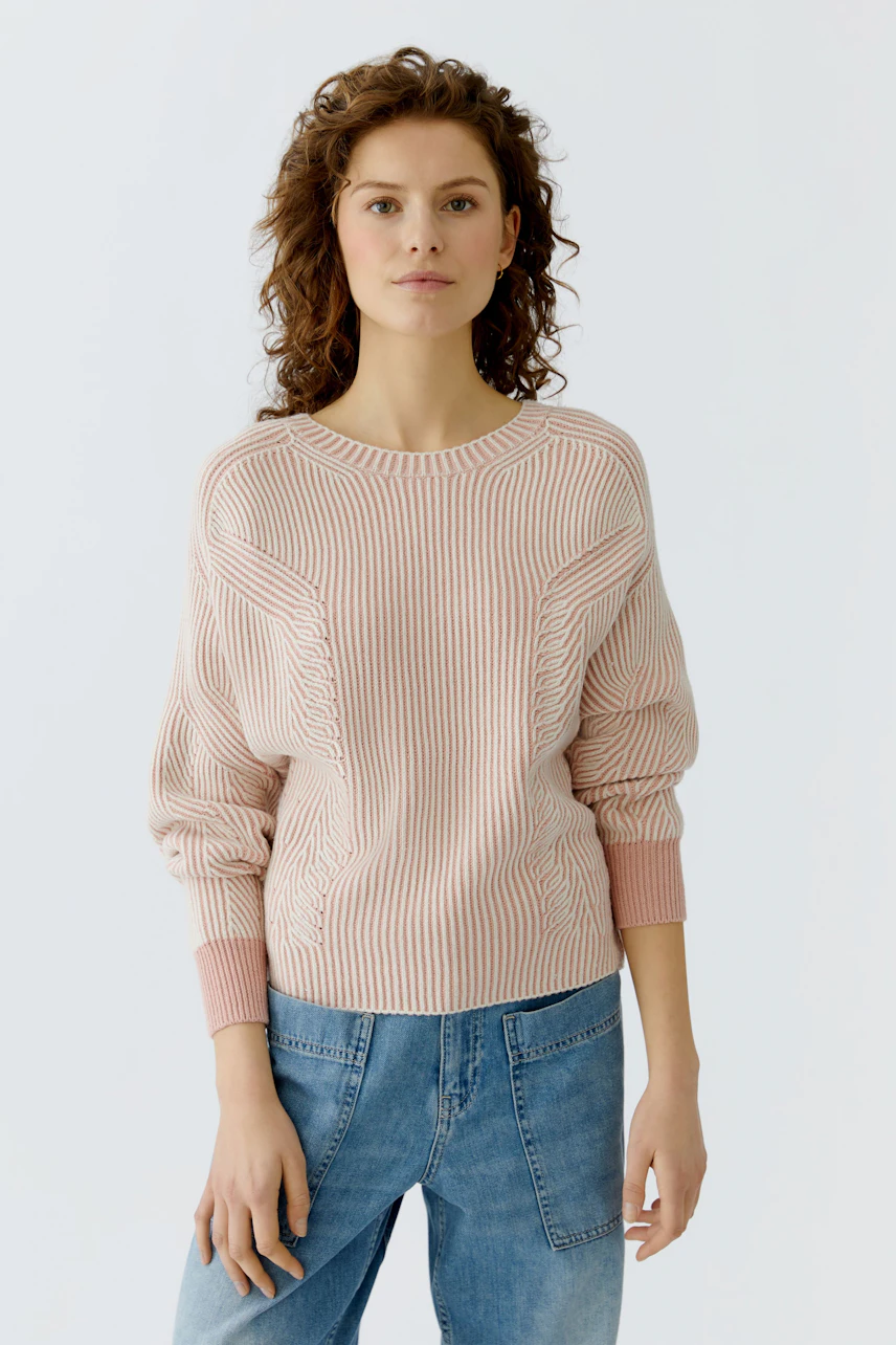 Casual women's pullover: A woman in a light pink ribbed pullover with relaxed fit and stylish details.