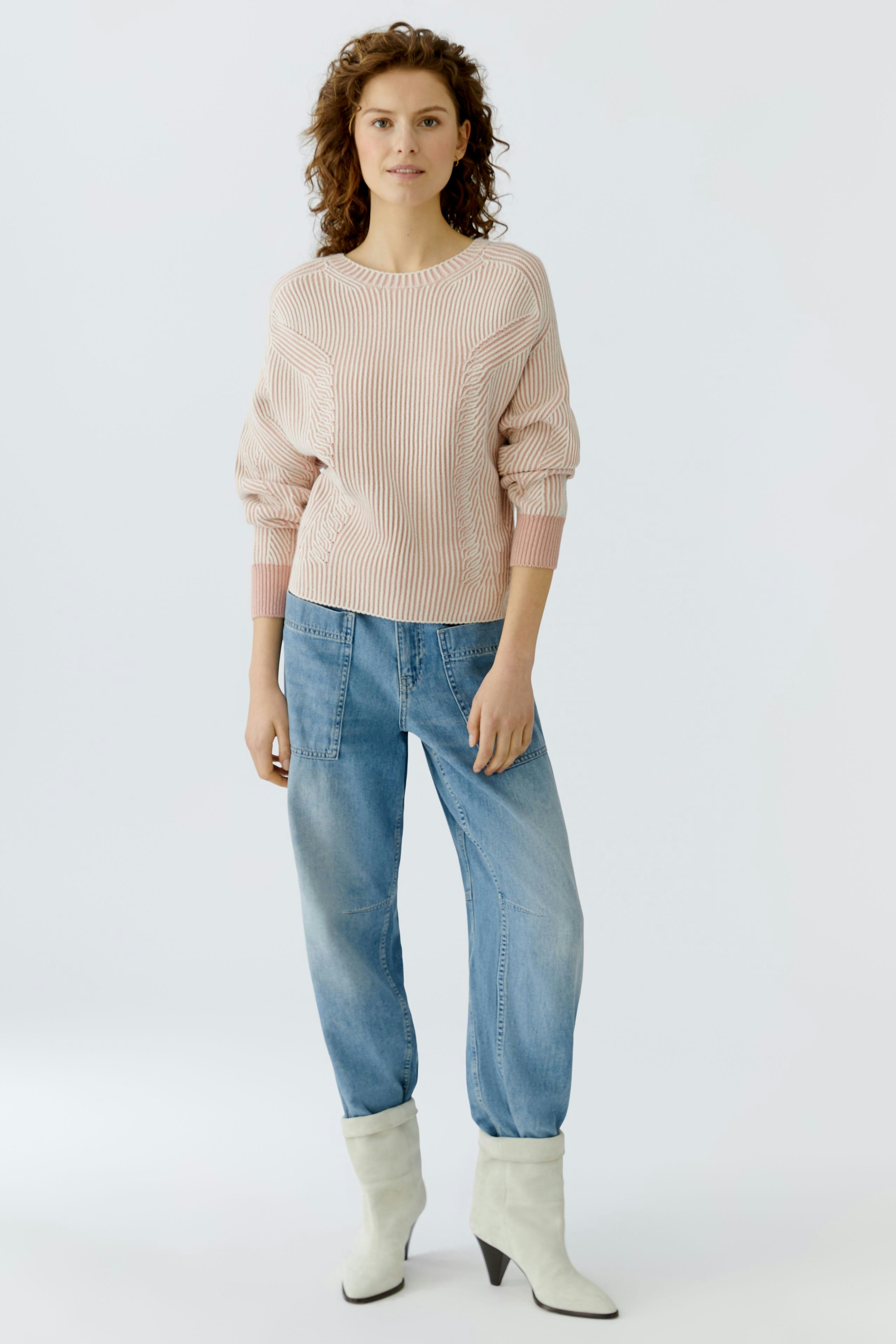 Casual women's pullover: Young woman in a pink ribbed pullover with balloon sleeves and relaxed jeans.