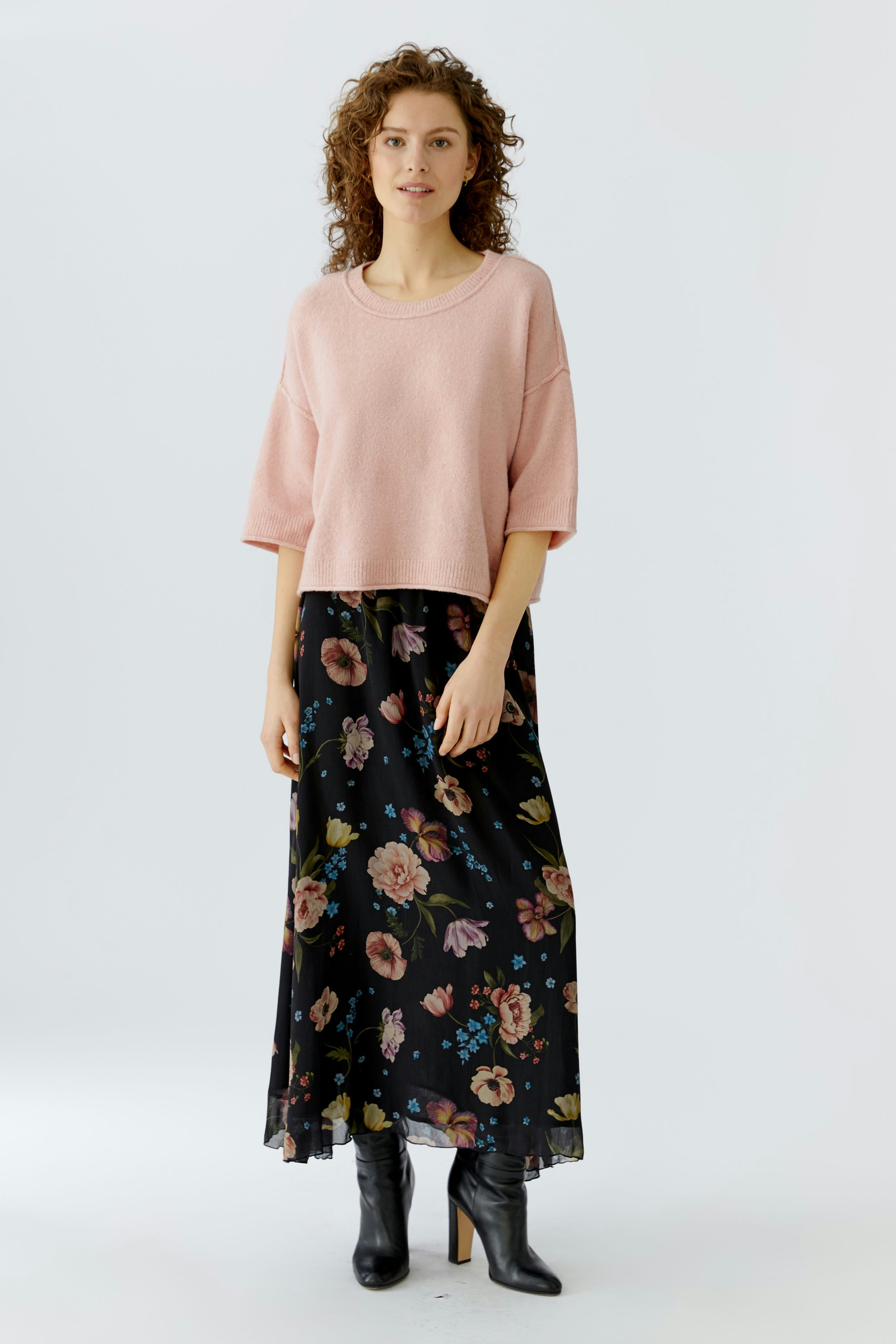 Casual women's pullover: Young woman in a pink oversized pullover paired with a floral maxi skirt.
