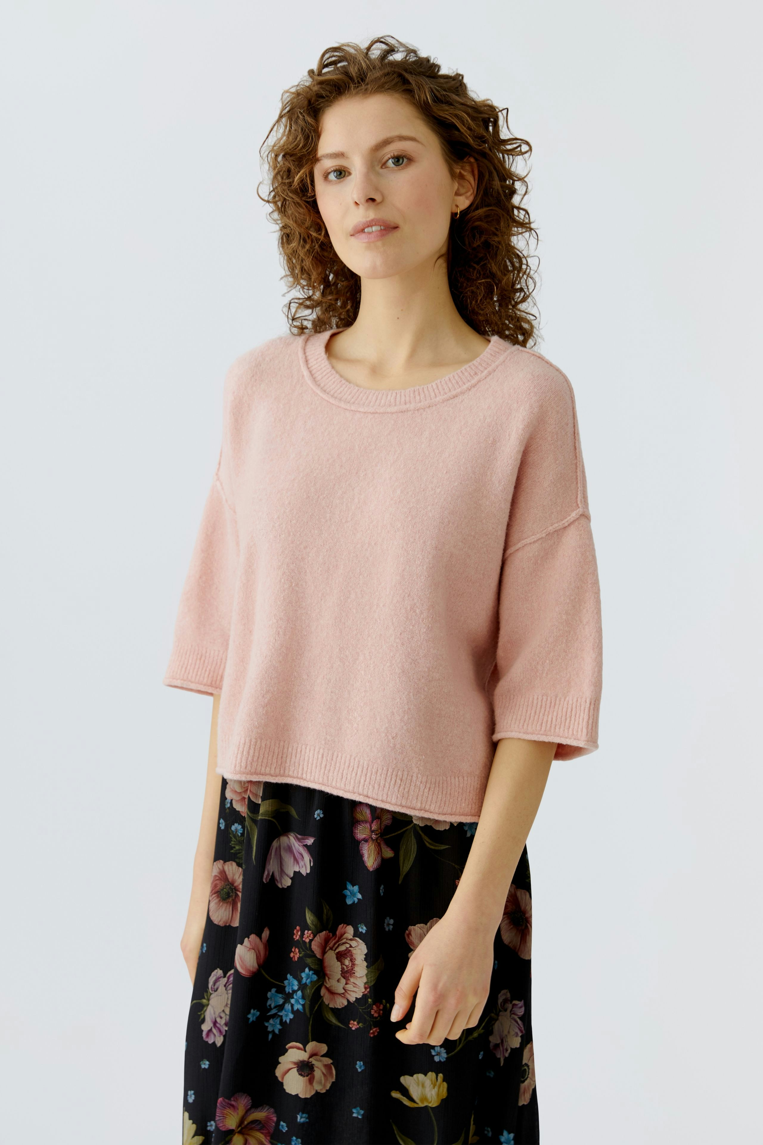 Casual women's pullover: A woman in a soft pink pullover paired with a floral skirt, exuding a relaxed vibe.