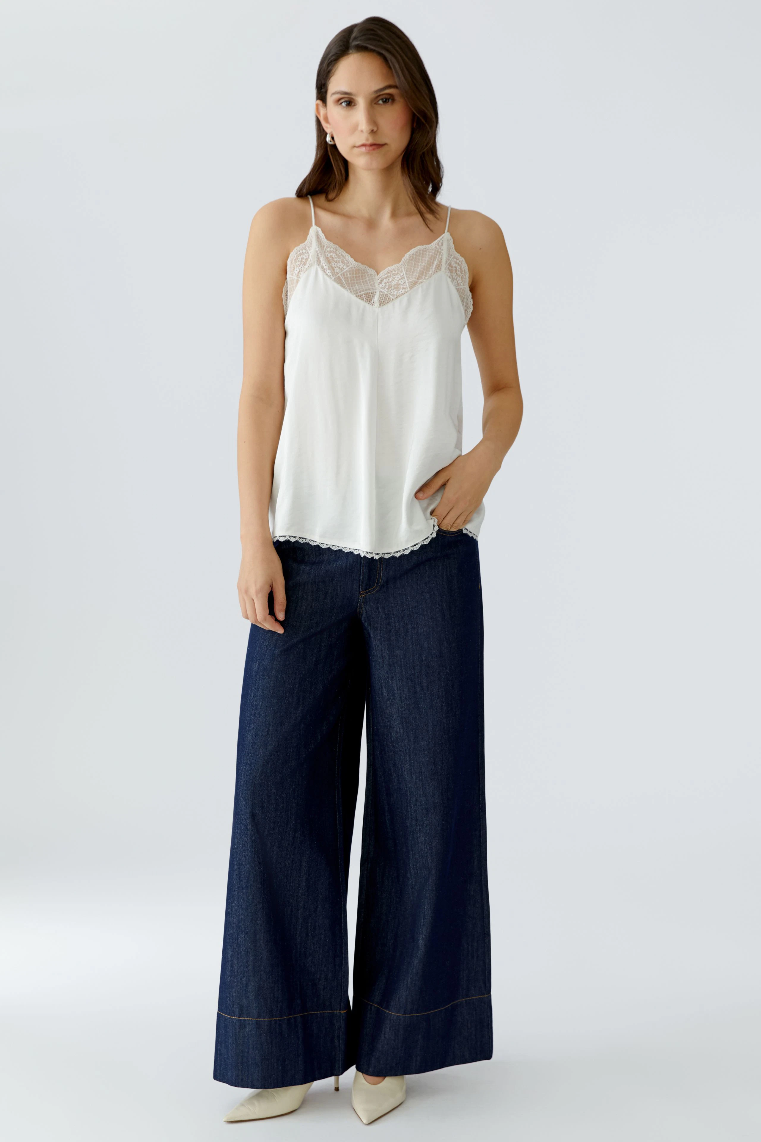 Lightweight women's top with lace details, paired with wide-leg jeans, showcasing a casual style.