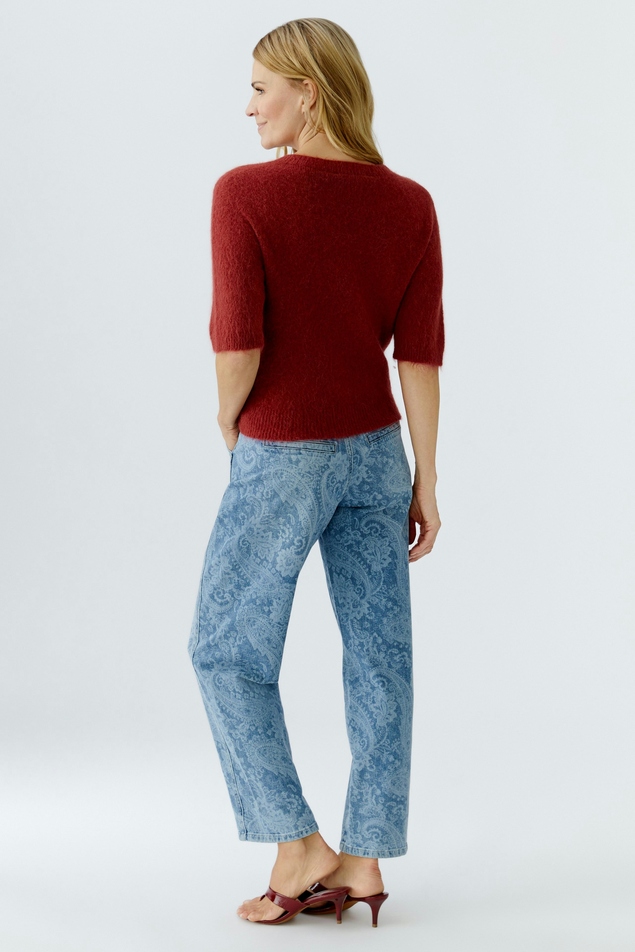 Damen-Pullover in Rot: Frau mit kurzem Ärmel und lässiger Jeans von hinten.