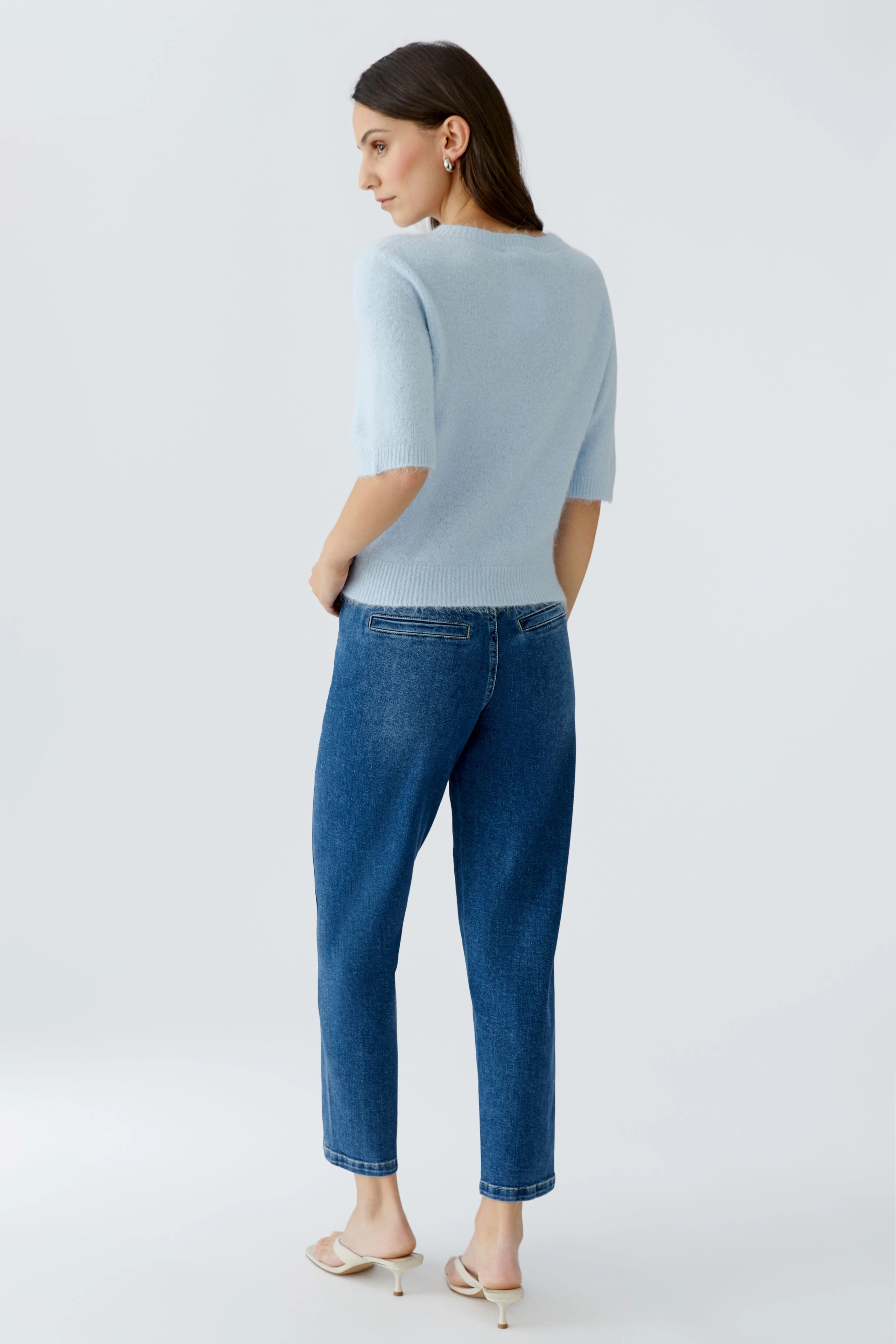 Damen-Pullover: Frau in hellblauem, kurzärmligem Pullover mit lässiger Jeans und Sandalen.