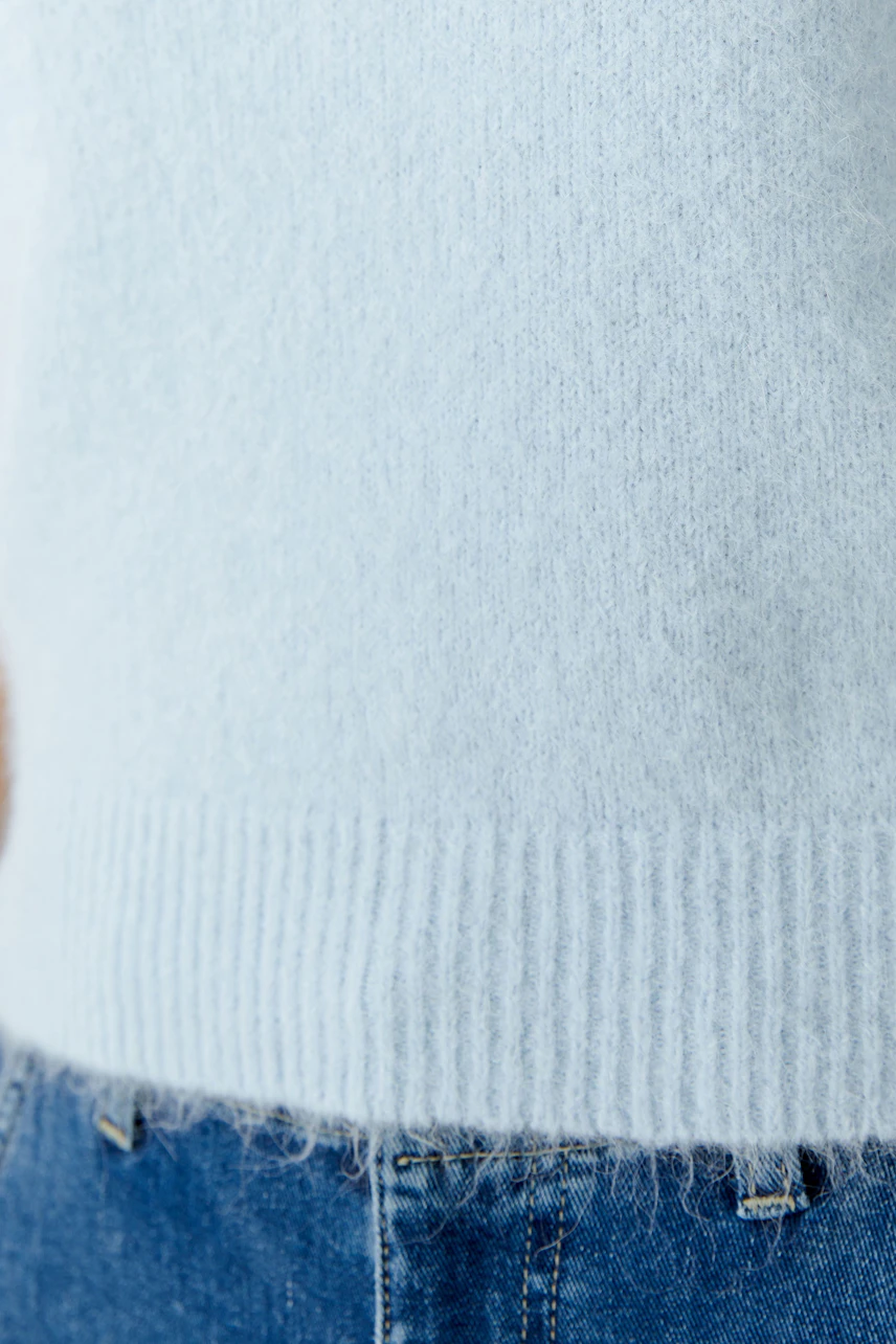 Heller Damen-Pullover: Frau trägt einen weichen, blauen Pullover mit lässigem Schnitt und Rippbündchen.