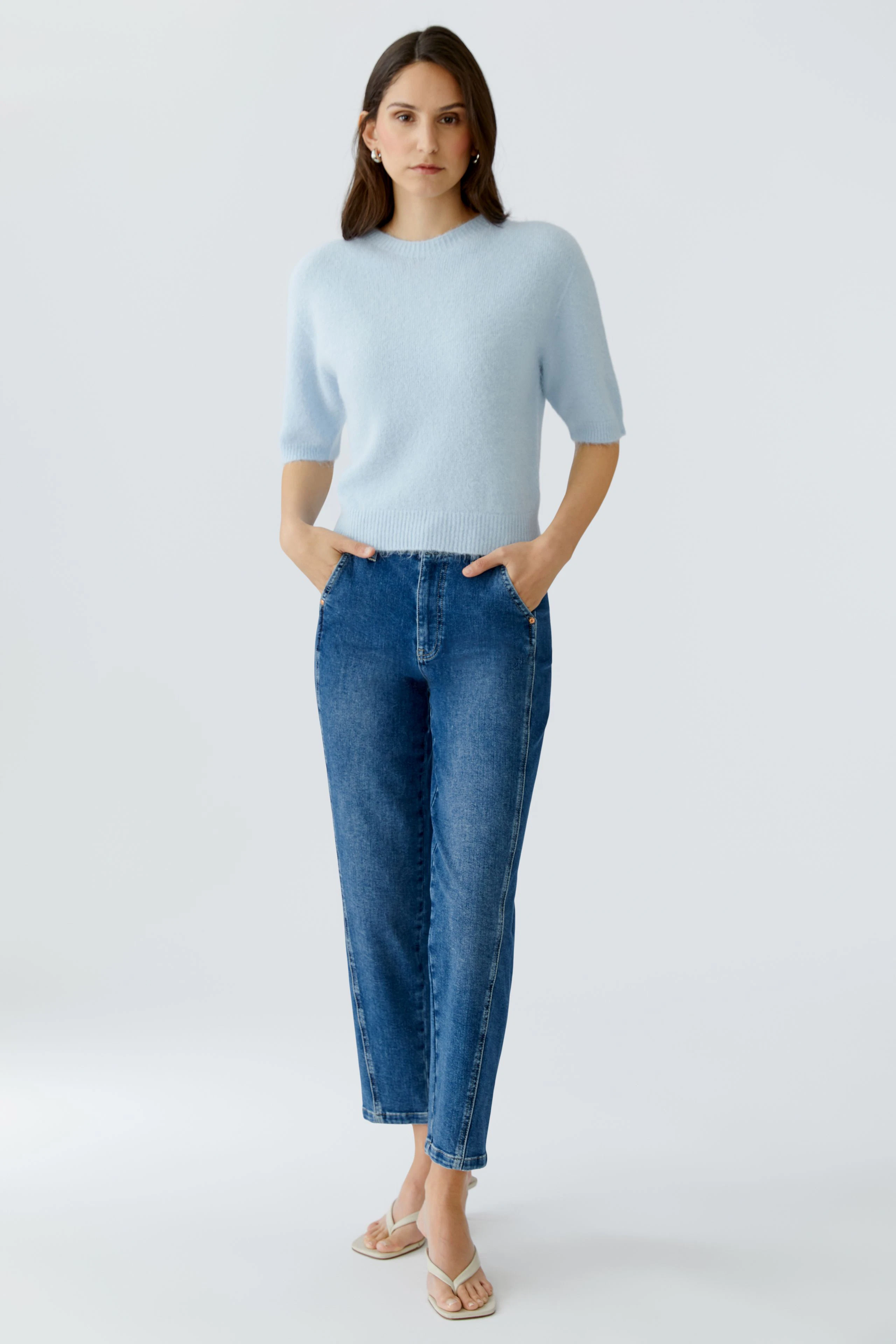 Casual women's pullover: A woman in a light blue pullover with short sleeves and relaxed fit jeans.