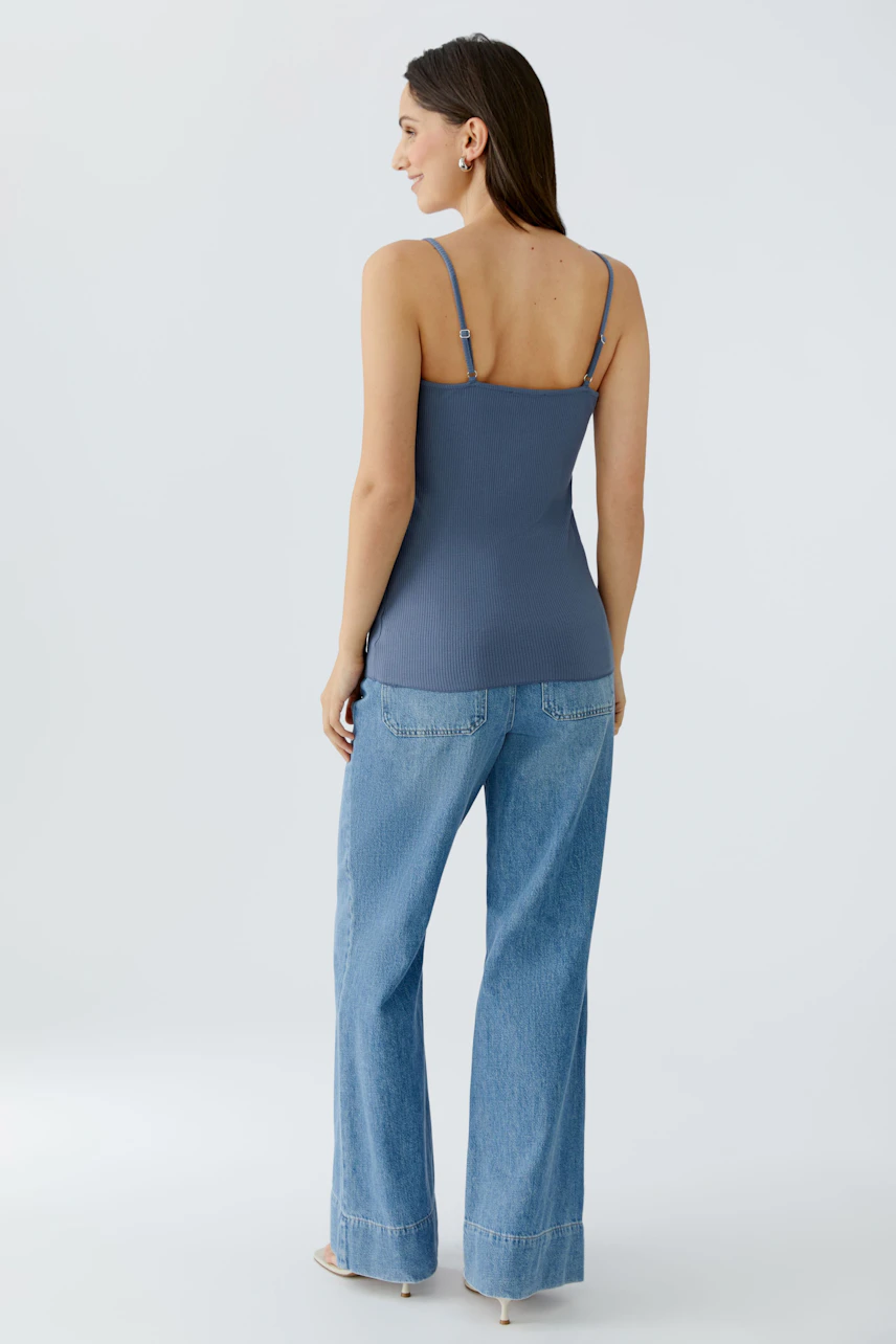 Casual women's top: Young woman in a blue tank top and wide-leg jeans, showcasing a relaxed style.