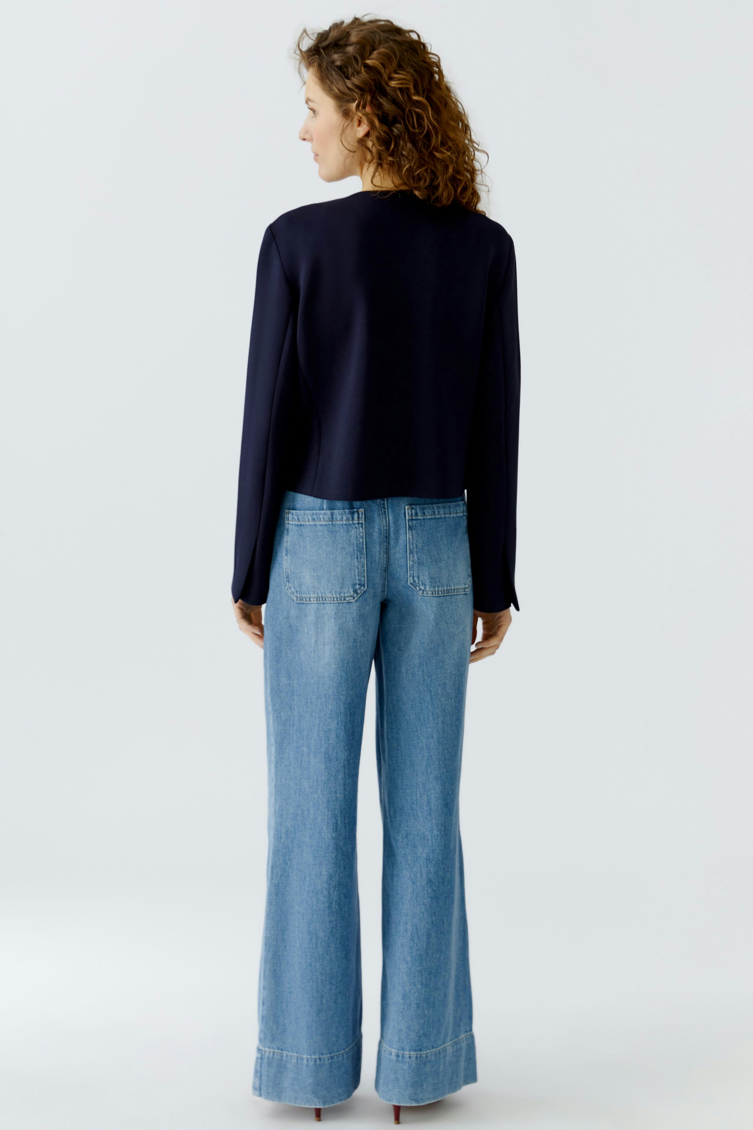 Casual women's jacket: A woman in a navy jacket paired with wide-leg jeans, showcasing a relaxed style.