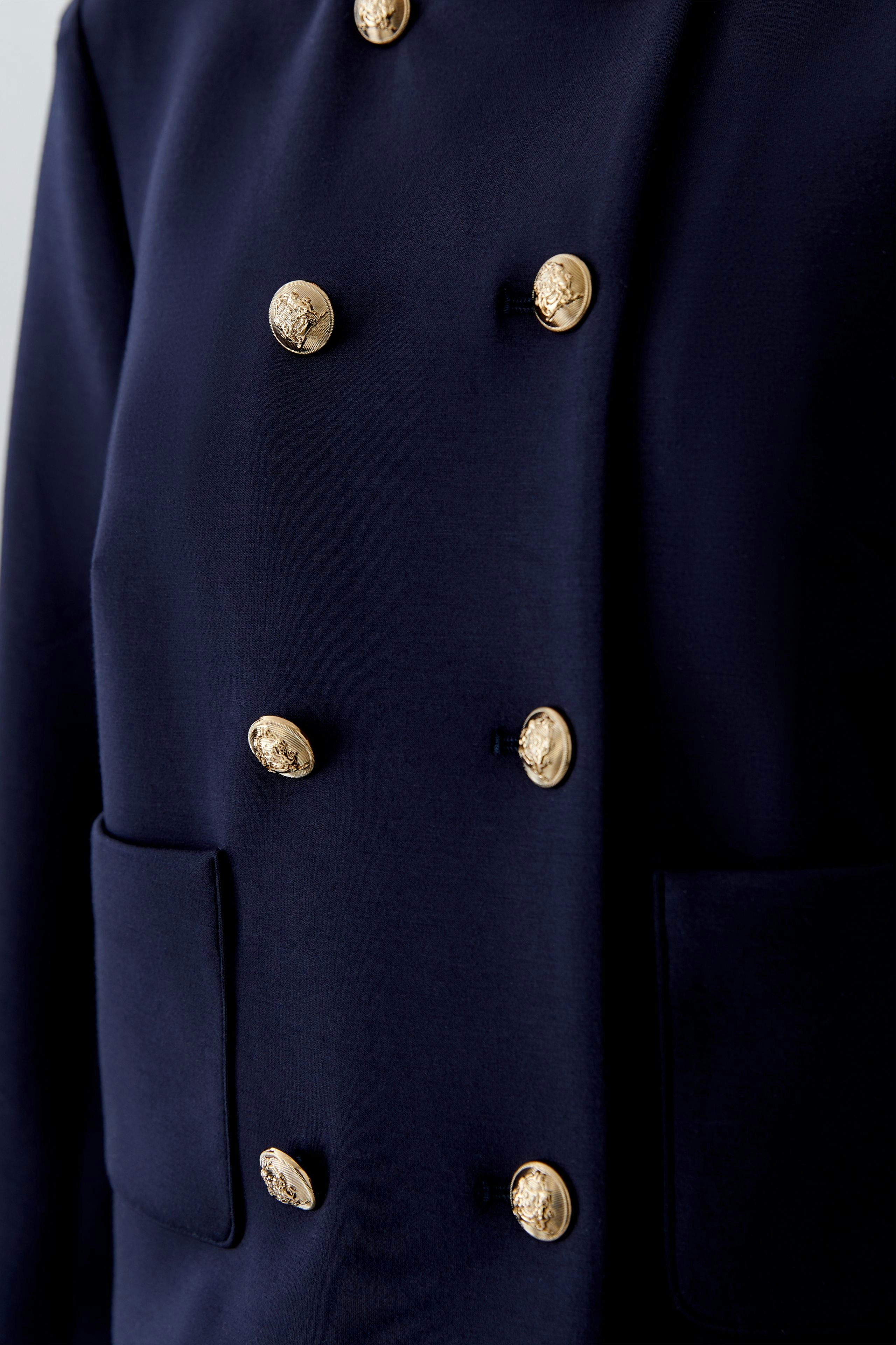 Stylish women's jacket: Close-up of a navy jacket with gold buttons and pockets.