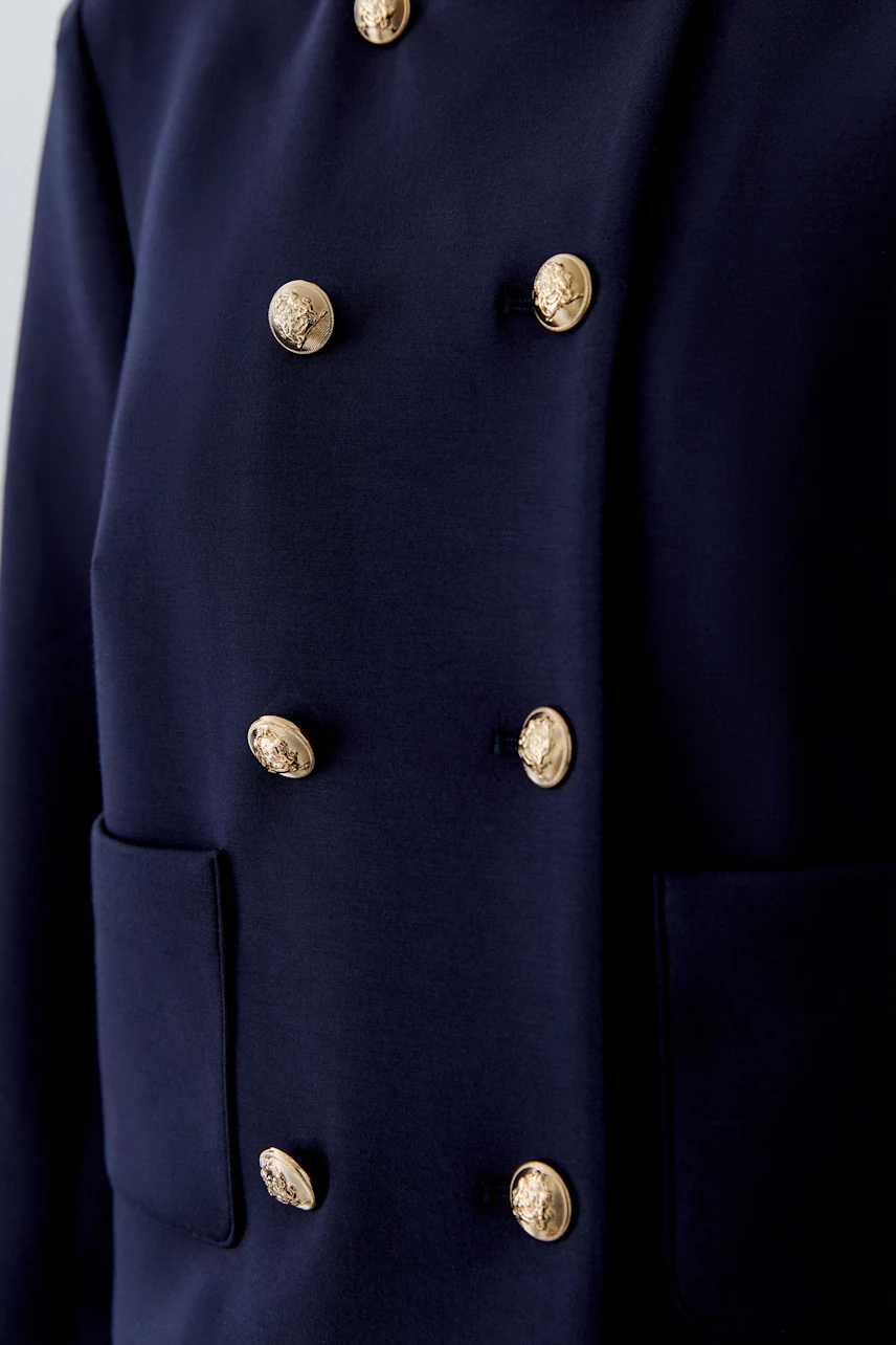 Stylish women's jacket: Close-up of a navy jacket with gold buttons and pockets.