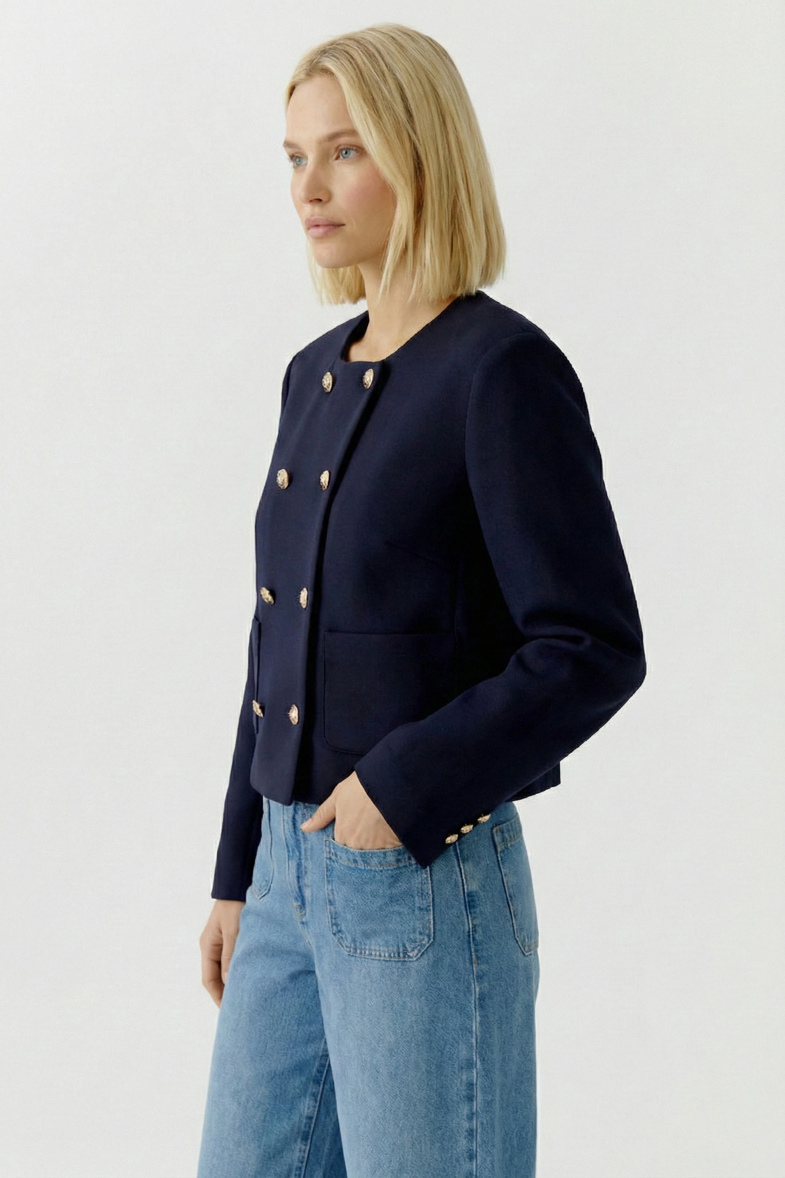 Casual women's jacket: A woman in a navy jacket with gold buttons and pockets, paired with jeans.