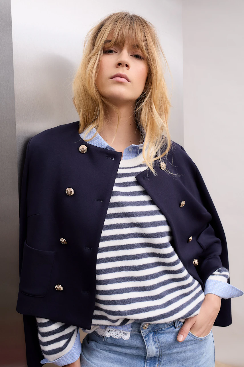 Modern women's jacket: A woman in a navy jacket over a striped pullover, exuding a casual vibe.