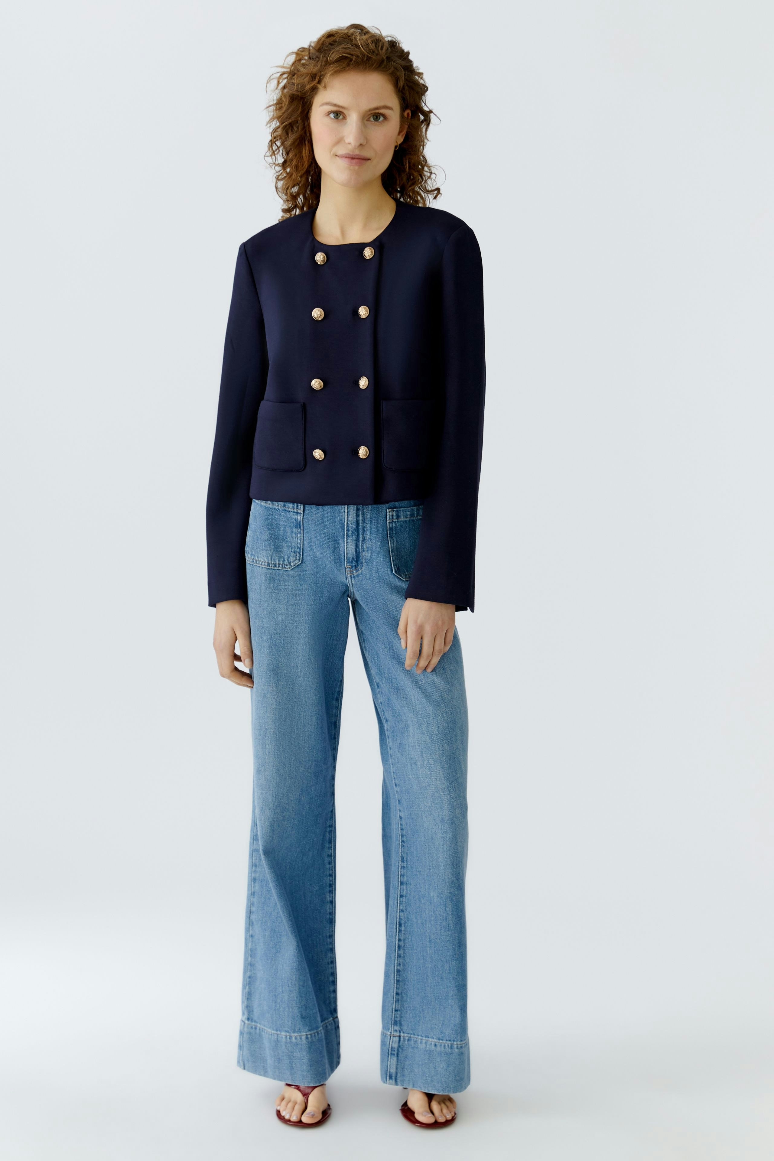 Casual women's jacket: A woman in a navy jacket with gold buttons and pockets, paired with wide-leg jeans.