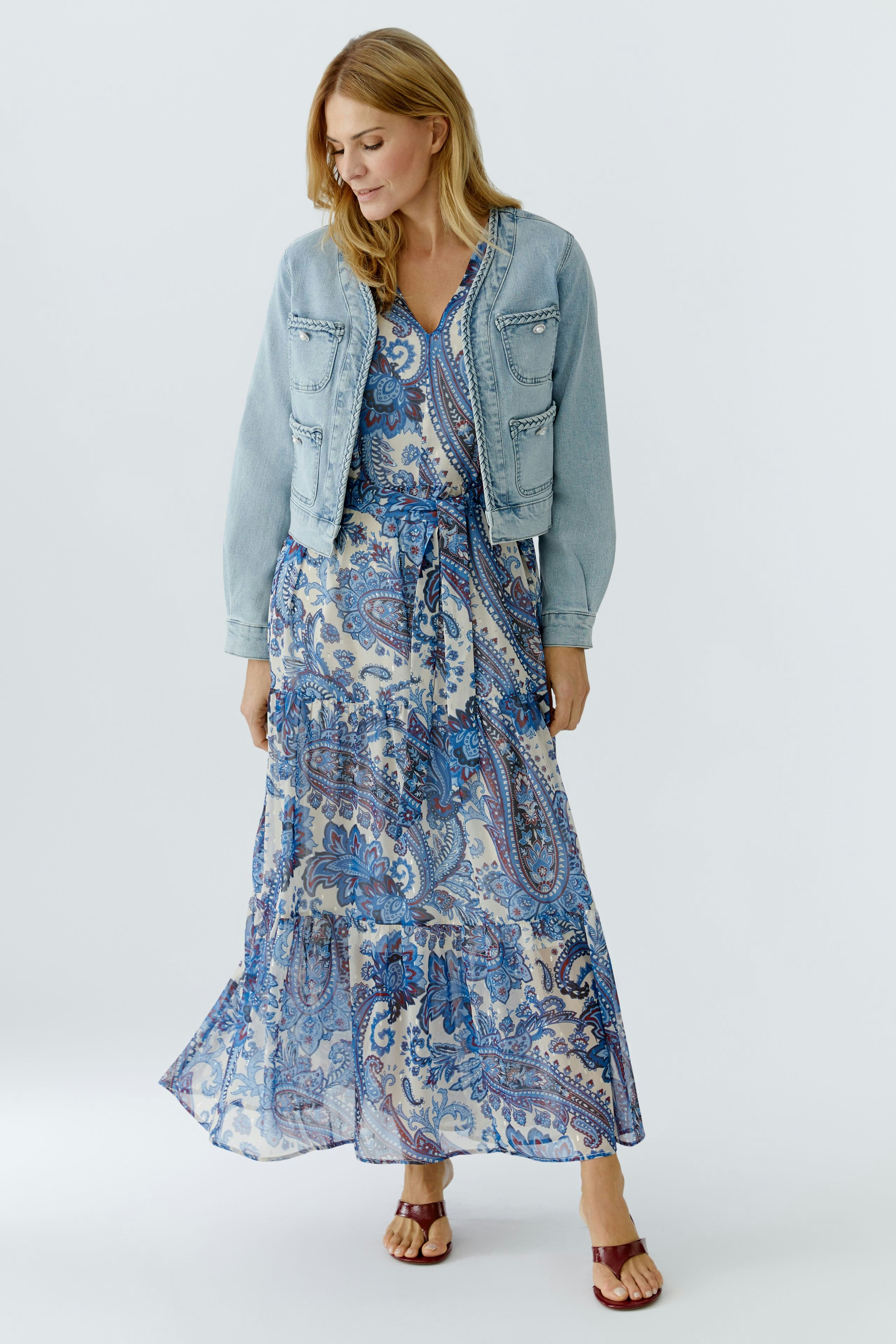 Casual women's denim jacket: A woman in a light blue jacket over a patterned dress, showcasing a relaxed style.