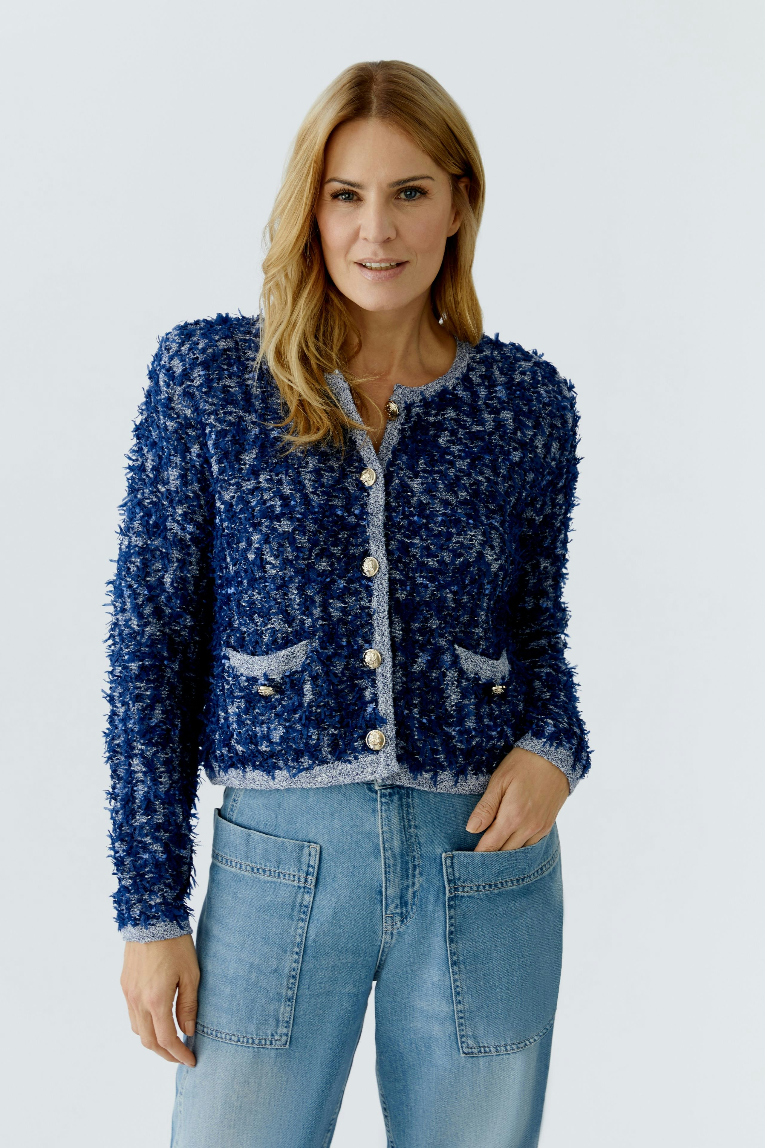 Casual women's cardigan: A woman in a blue textured cardigan with pockets and buttons, paired with jeans.