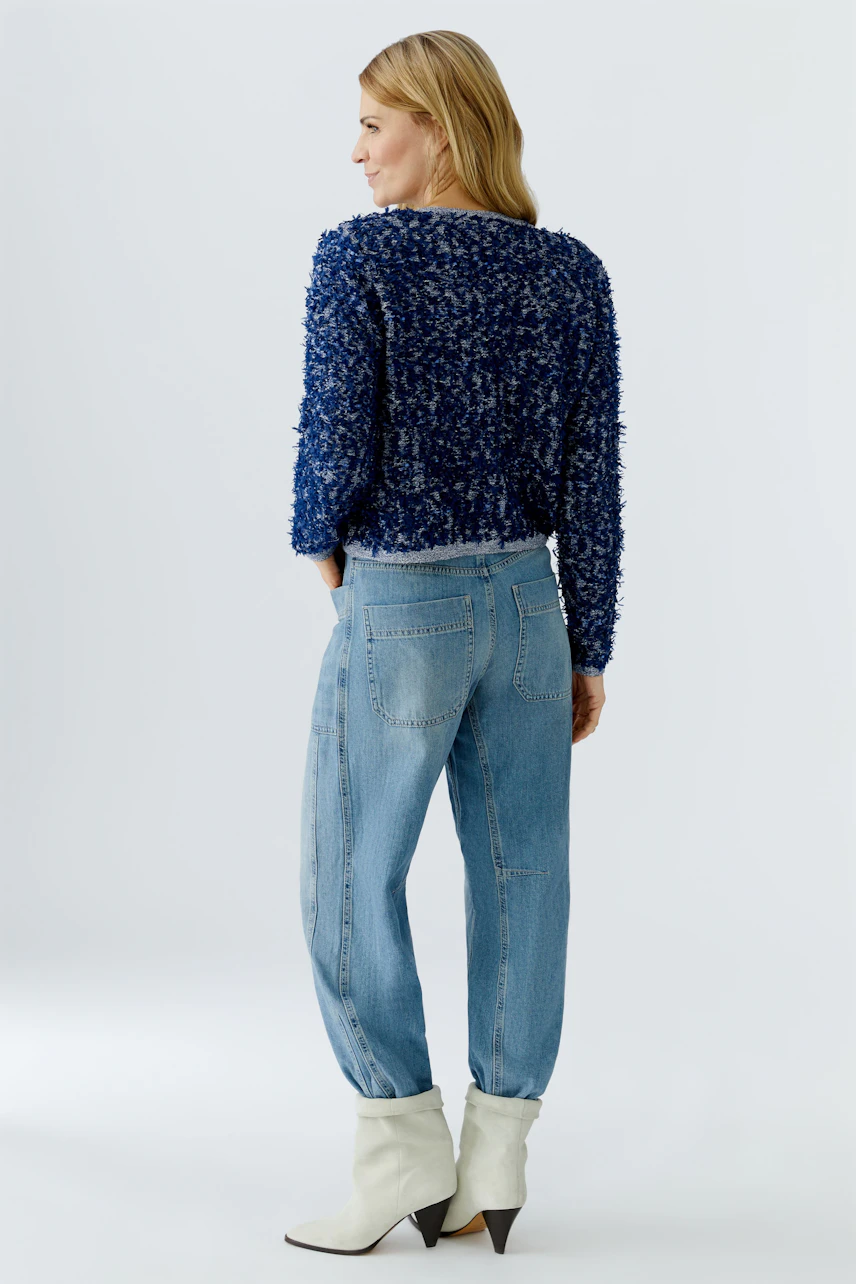 Casual women's cardigan: A woman in a blue textured cardigan paired with relaxed jeans.
