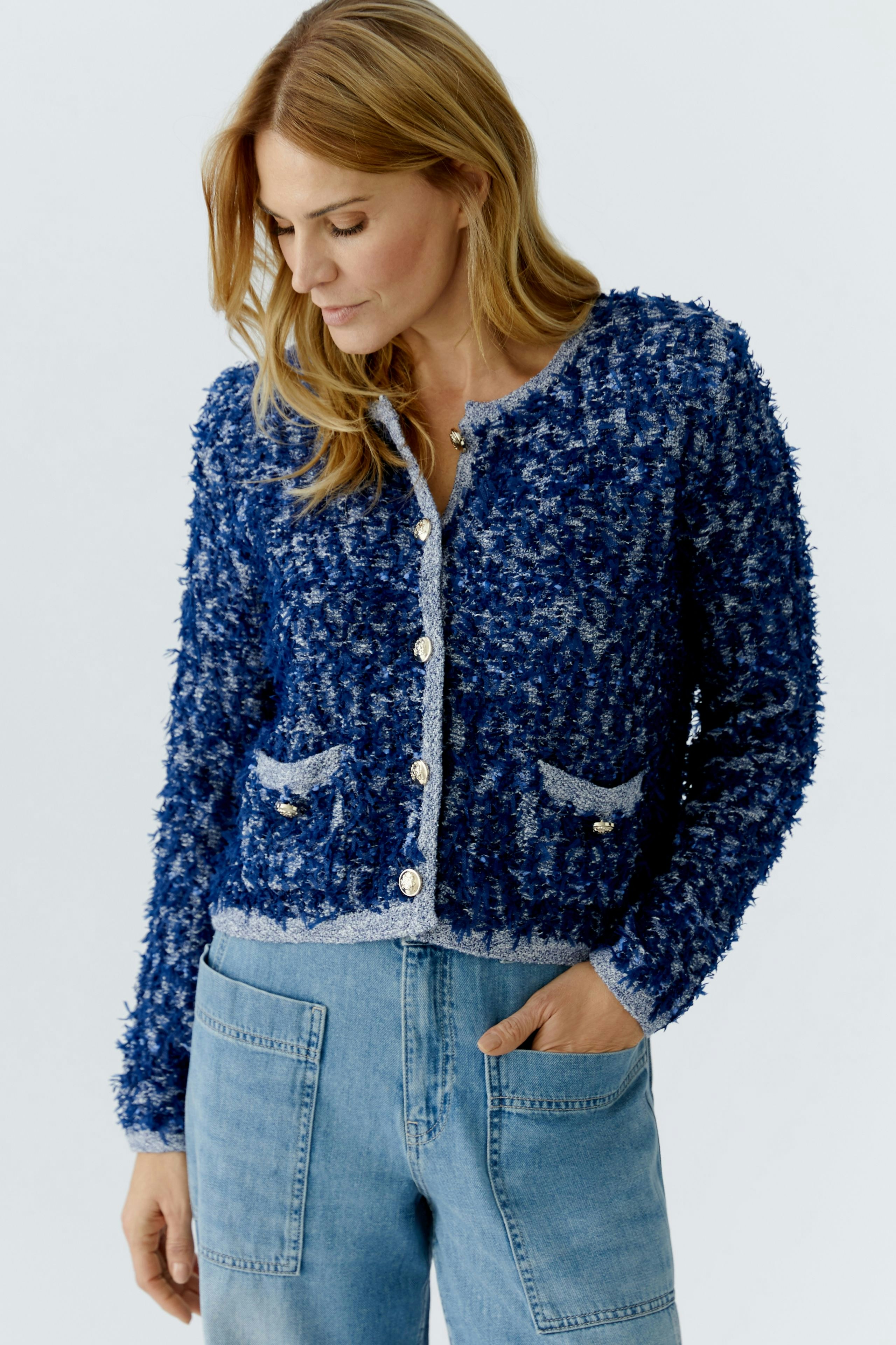Casual women's cardigan: A woman in a blue textured cardigan with pockets and buttons, paired with jeans.