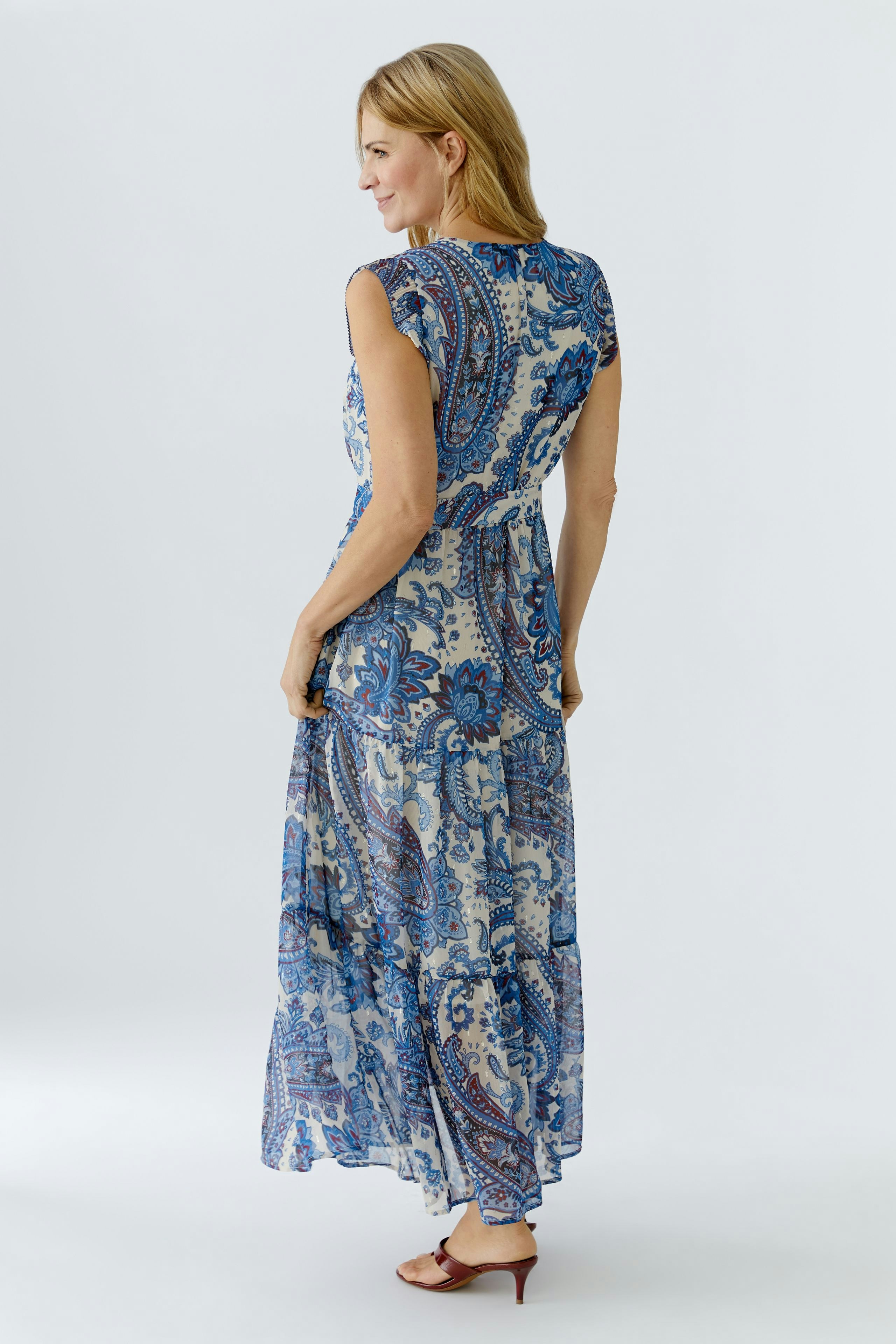 Stylish maxi dress: Woman in a blue patterned dress with short sleeves, showcasing a flowing design.