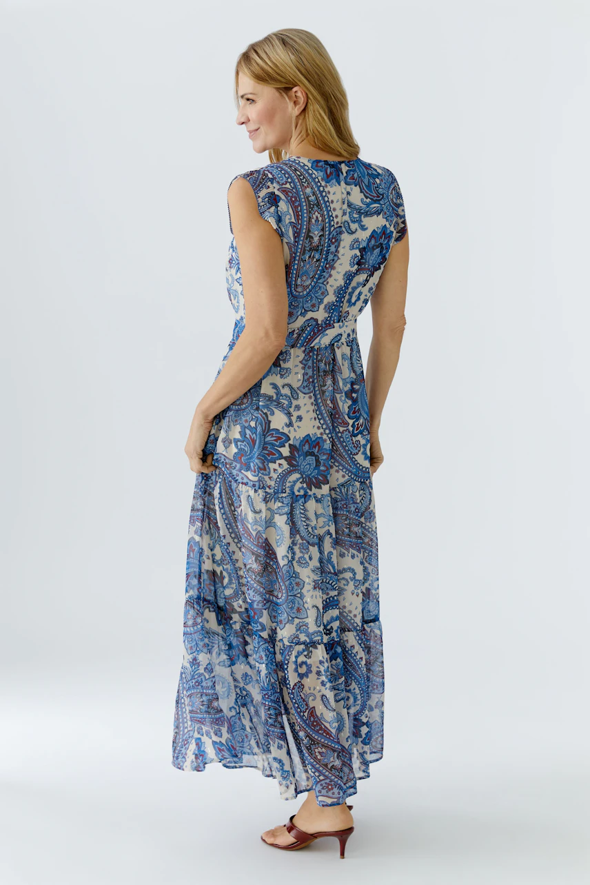 Stylish maxi dress: Woman in a blue patterned dress with short sleeves, showcasing a flowing design.