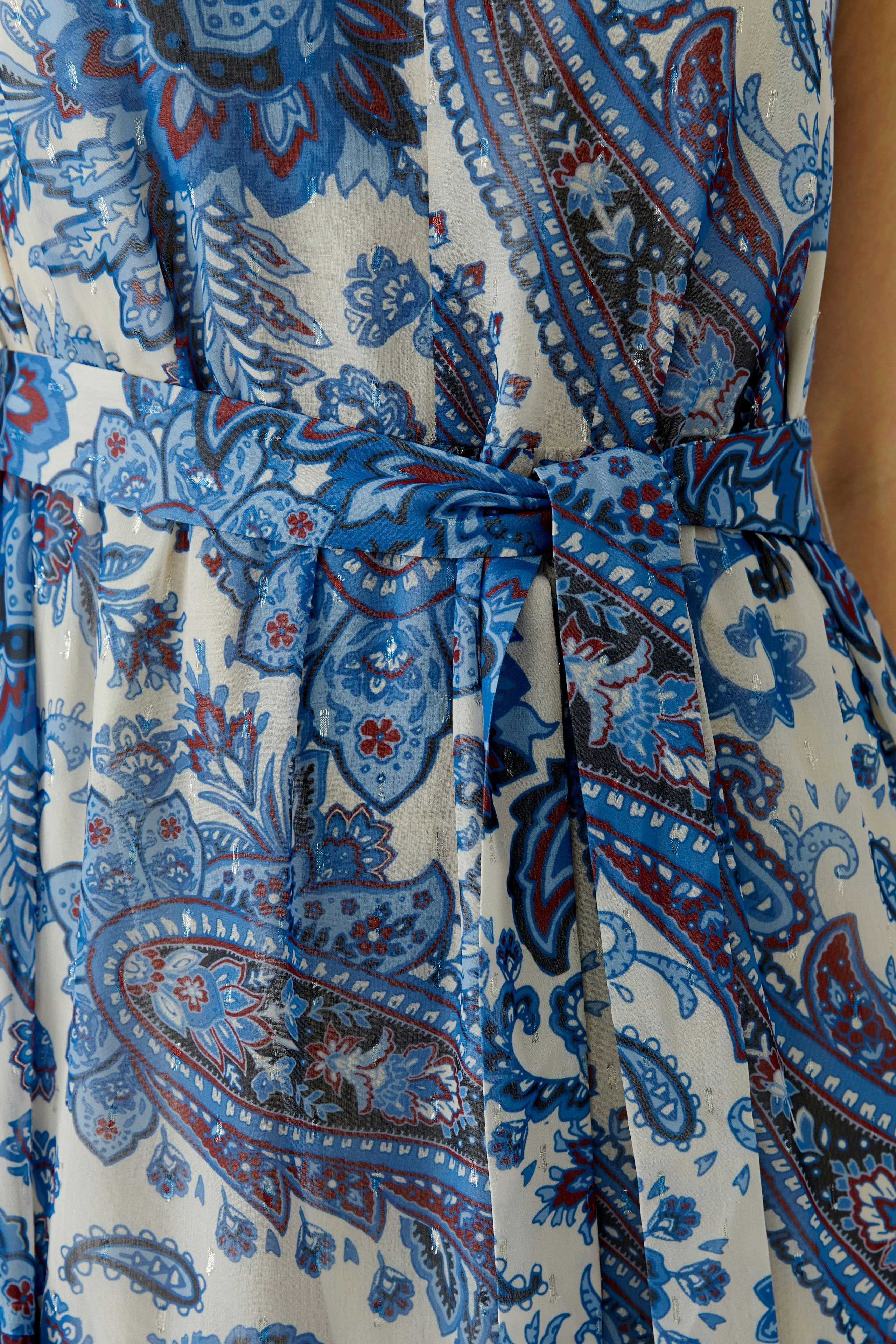 Maxi dress: Close-up of a woman wearing a blue patterned maxi dress with a tied waist.