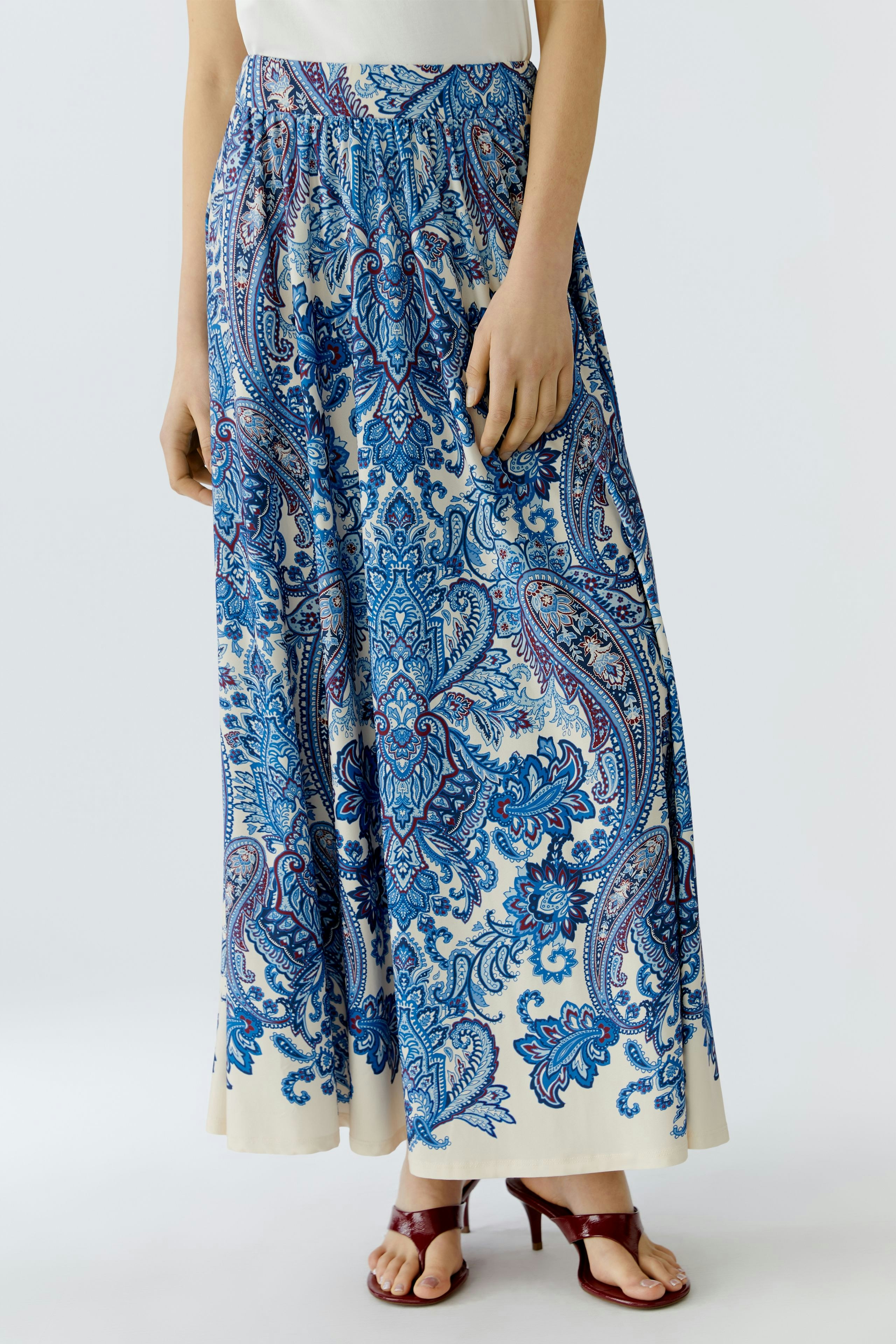 Flowy A-line skirt: Woman in a blue paisley print skirt, perfect for casual summer outings.