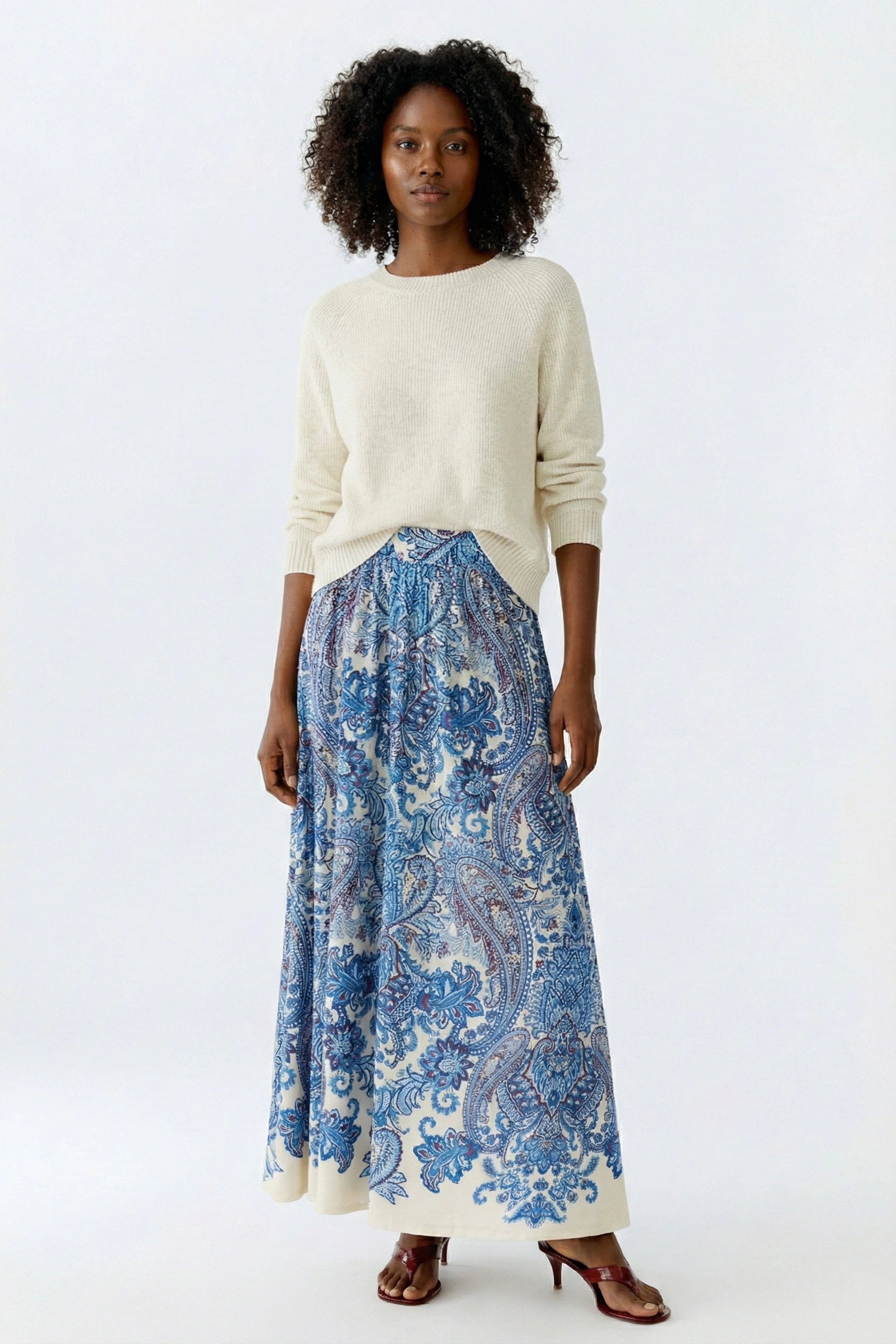 A-Linien-Rock: Junge Frau trägt einen bunten Rock mit Paisleymuster und lässigem Pullover.