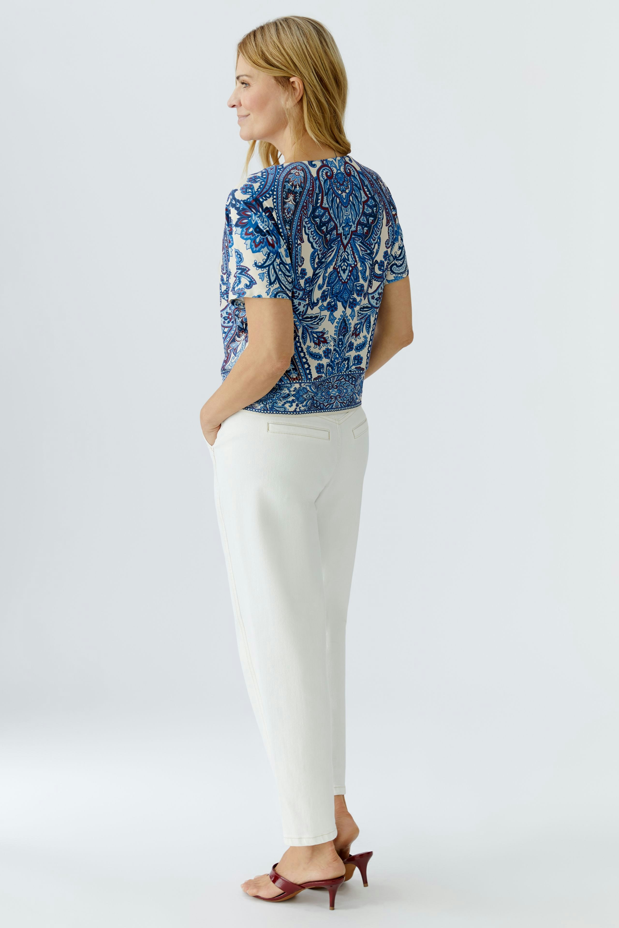 Casual women's blouse shirt: Woman in a blue patterned top paired with white trousers, showcasing a relaxed style.