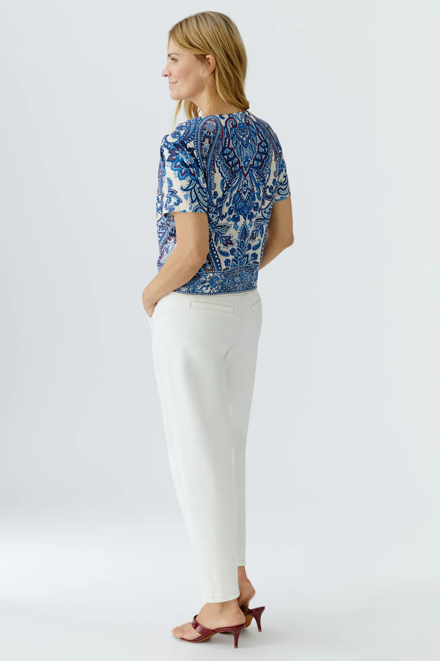 Casual women's blouse shirt: Woman in a blue patterned top paired with white trousers, showcasing a relaxed style.