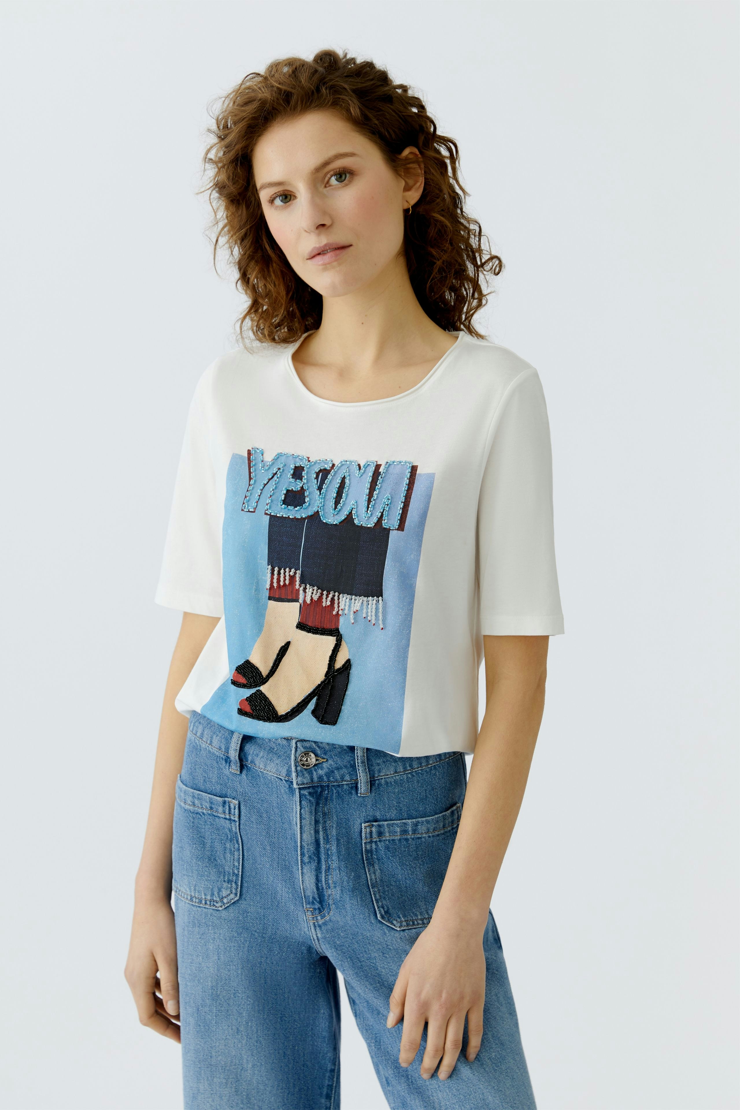 Casual women's T-shirt: Young woman in a white tee with graphic print and relaxed fit jeans.
