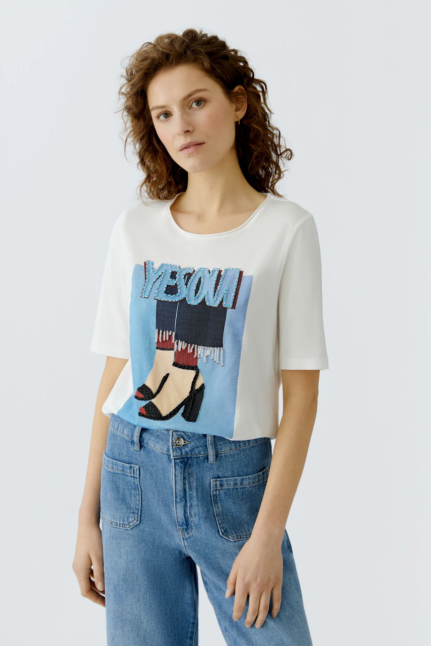 Casual women's T-shirt: Young woman in a white tee with graphic print and relaxed fit jeans.