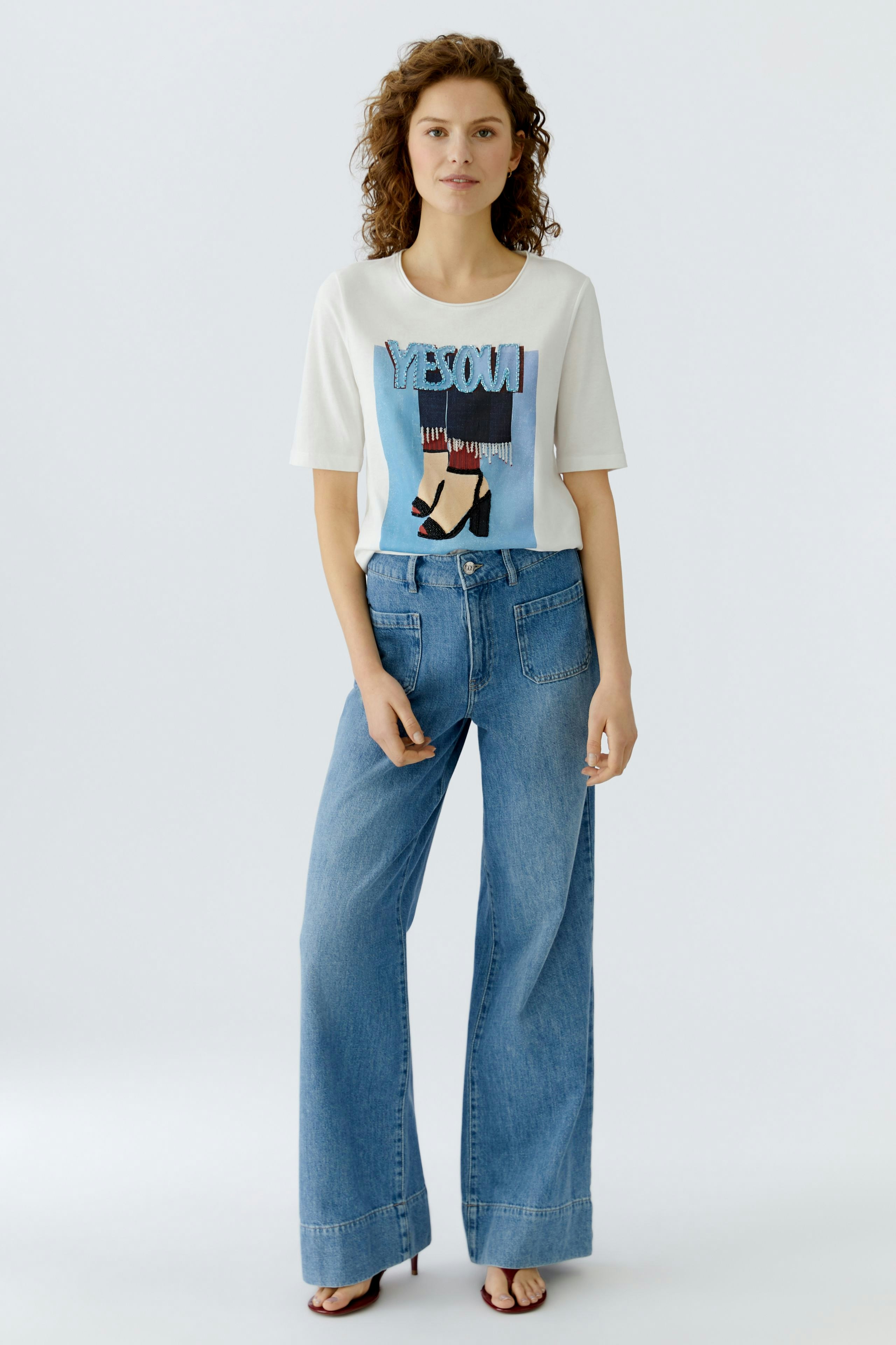 Casual women's T-shirt: Young woman in a graphic tee paired with wide-leg jeans, exuding a relaxed vibe.