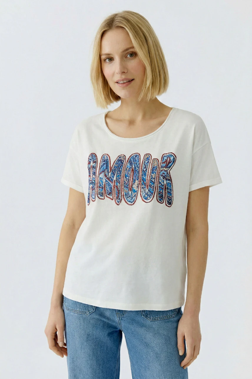 Casual women's T-shirt: Young woman in a white tee with 'AMOUR' print, paired with blue jeans.
