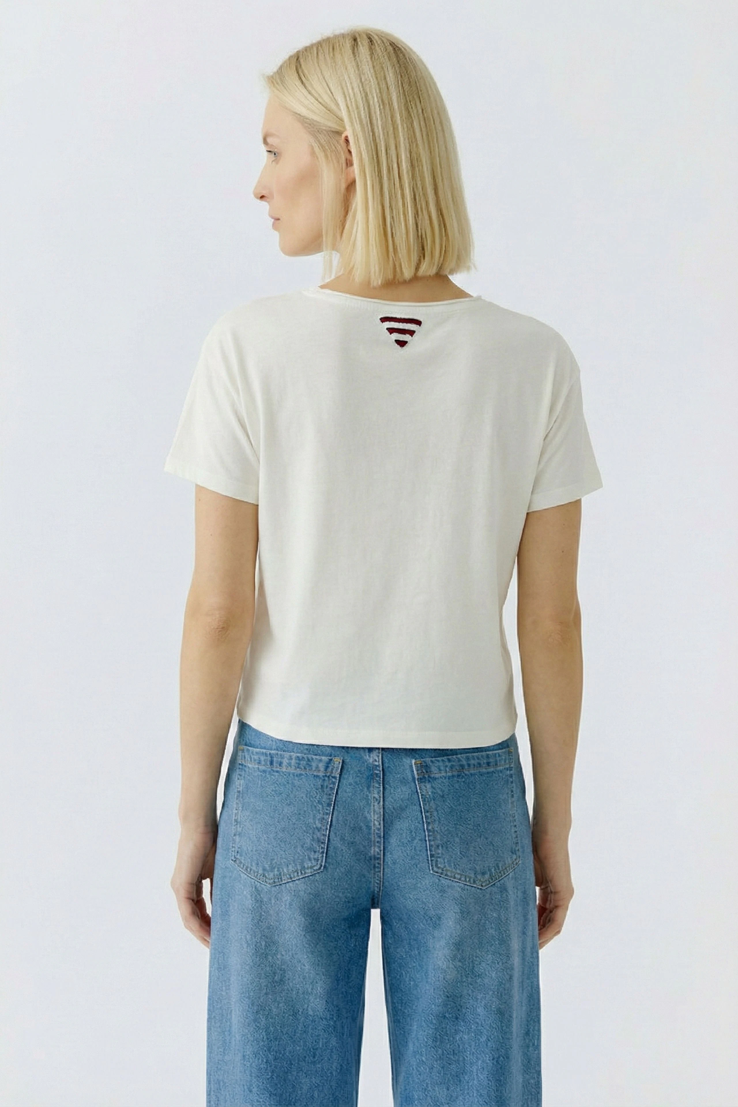 Casual women's T-shirt: A woman in a white T-shirt with a unique back design, paired with wide-leg jeans.