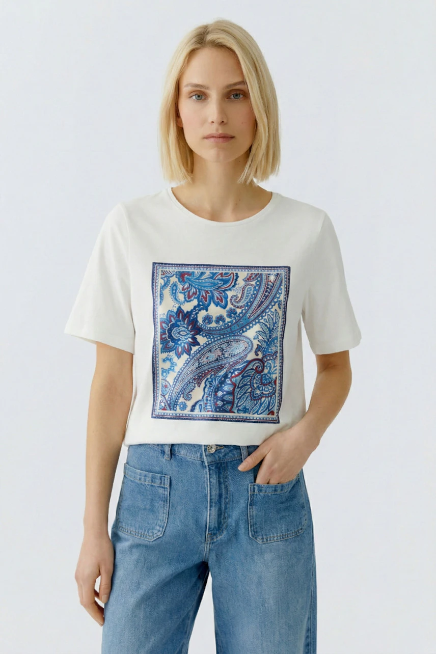 Damen-T-Shirt: Frau trägt ein weißes T-Shirt mit buntem Paisleymuster und lässigen Jeans.