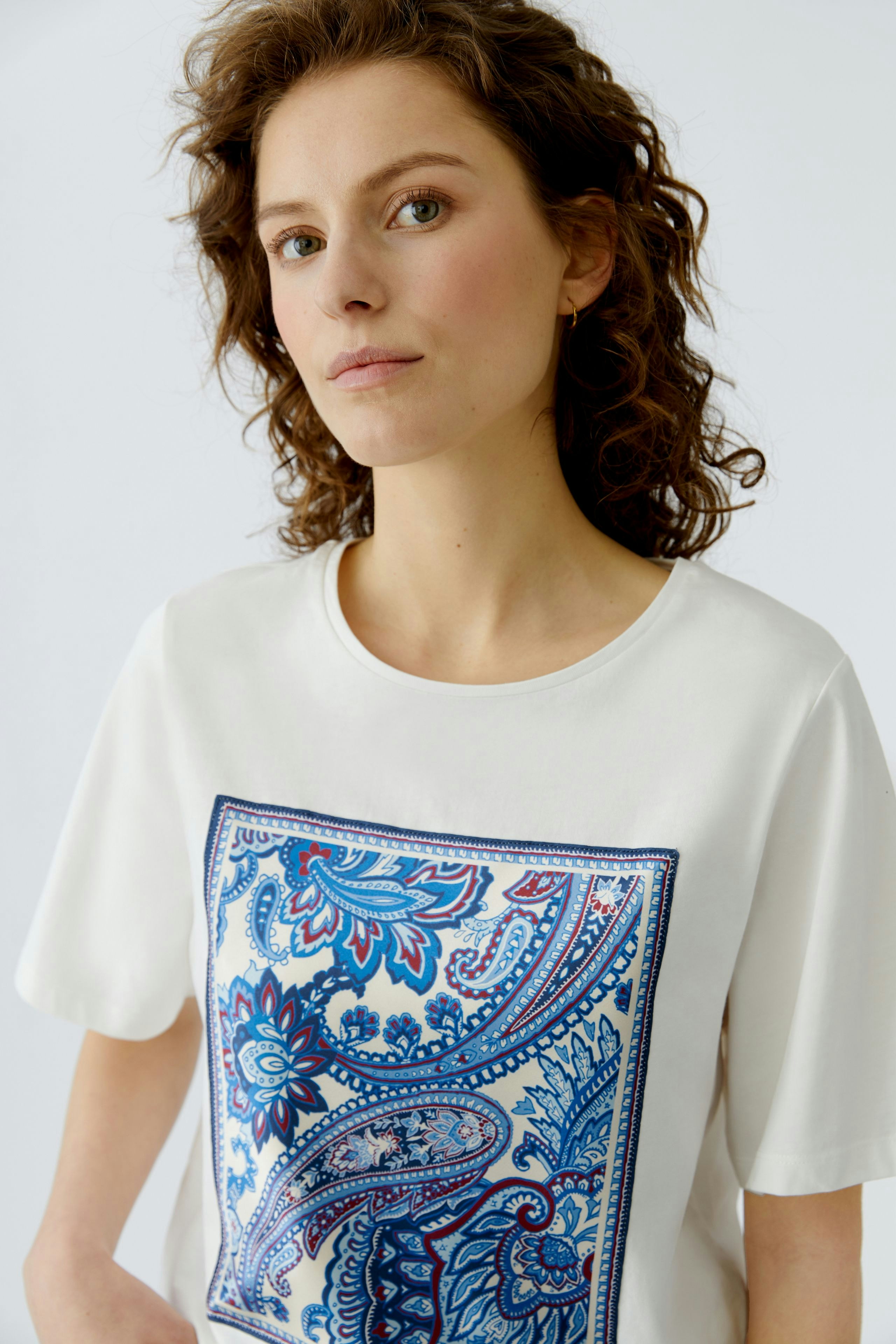 Casual women's T-shirt: Young woman in a white tee featuring a colorful paisley print.