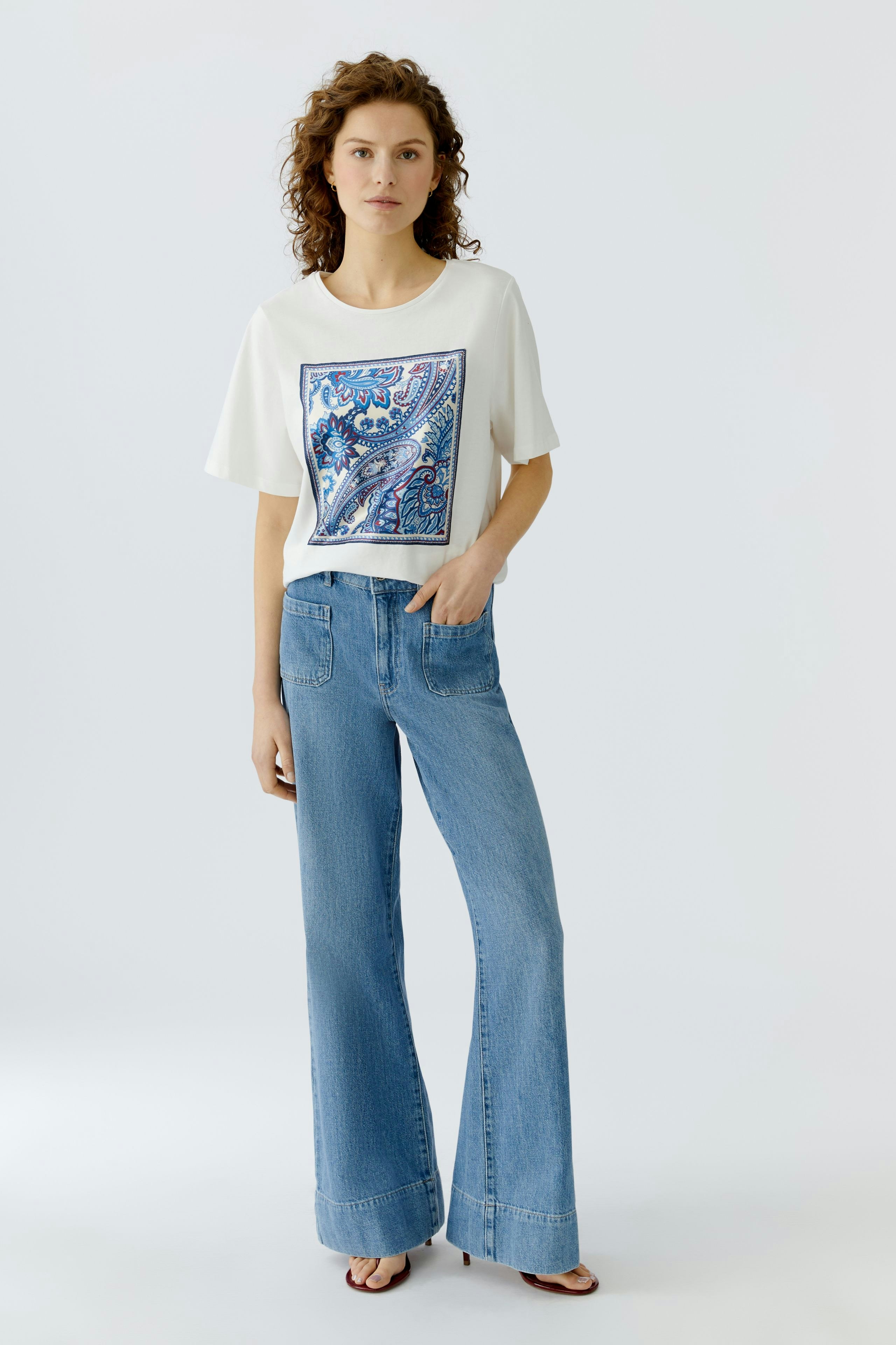 Casual women's T-shirt: A woman in a white T-shirt with a colorful print, paired with flared jeans.