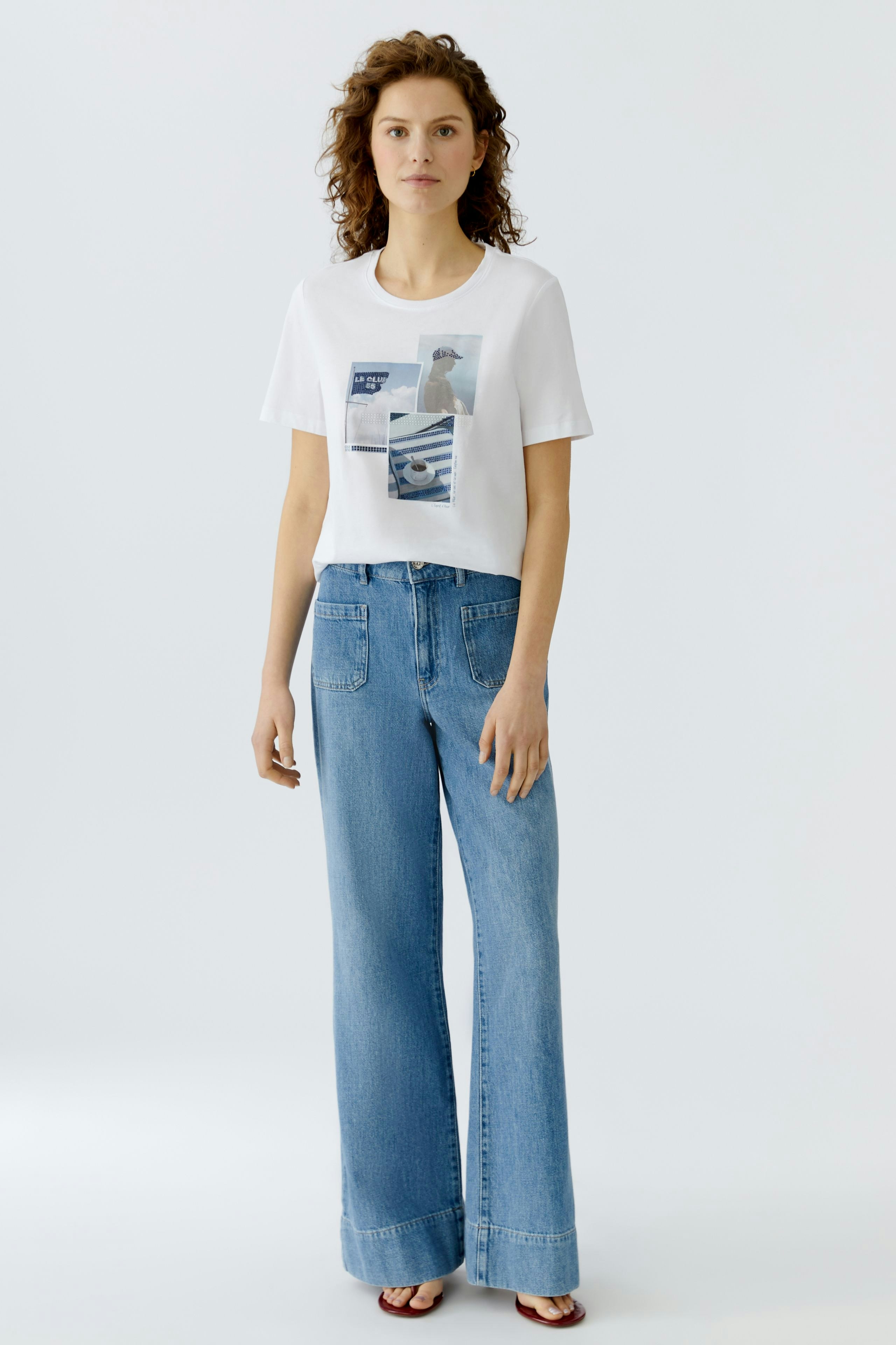 Casual women's T-shirt: Young woman in a white tee with graphic print, paired with wide-leg jeans.