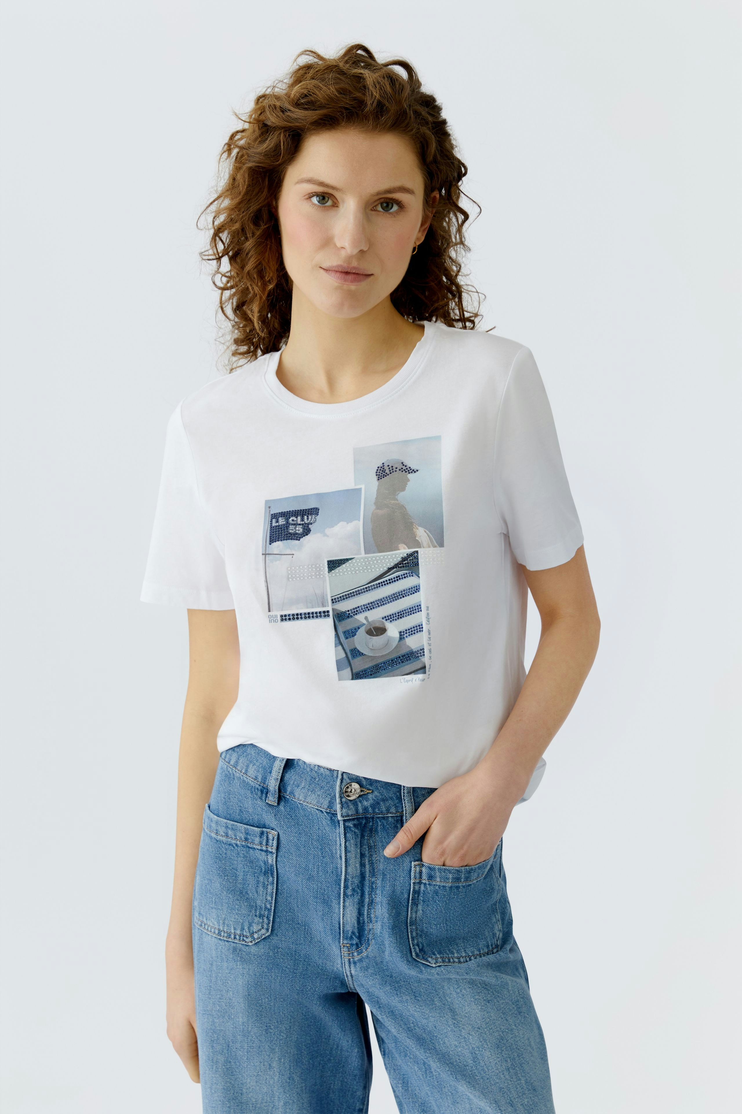 Casual women's T-shirt: Young woman in a white tee with graphic prints, paired with blue jeans.