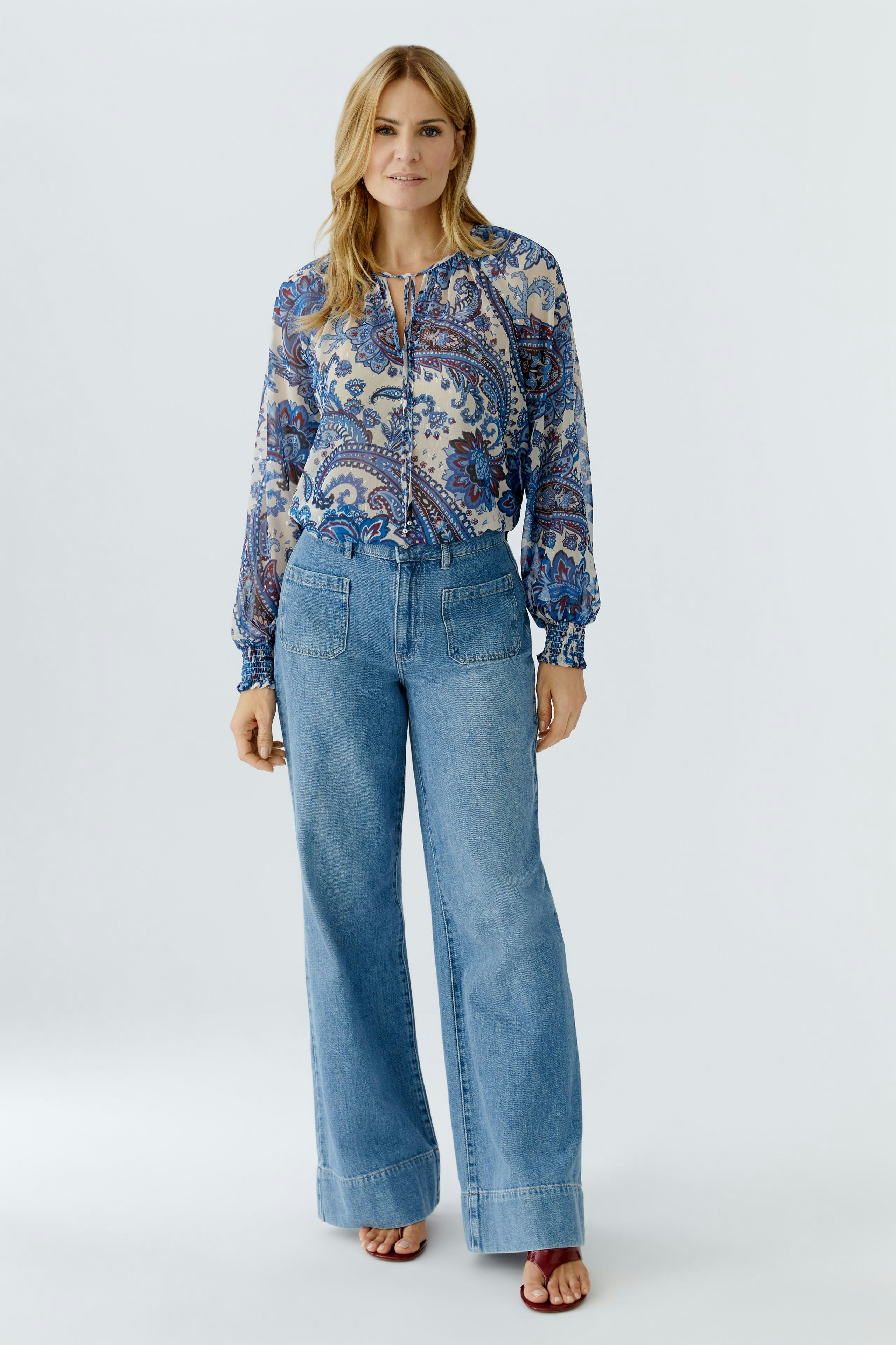 Casual women's blouse: Woman in a colorful patterned blouse with relaxed fit and balloon sleeves.