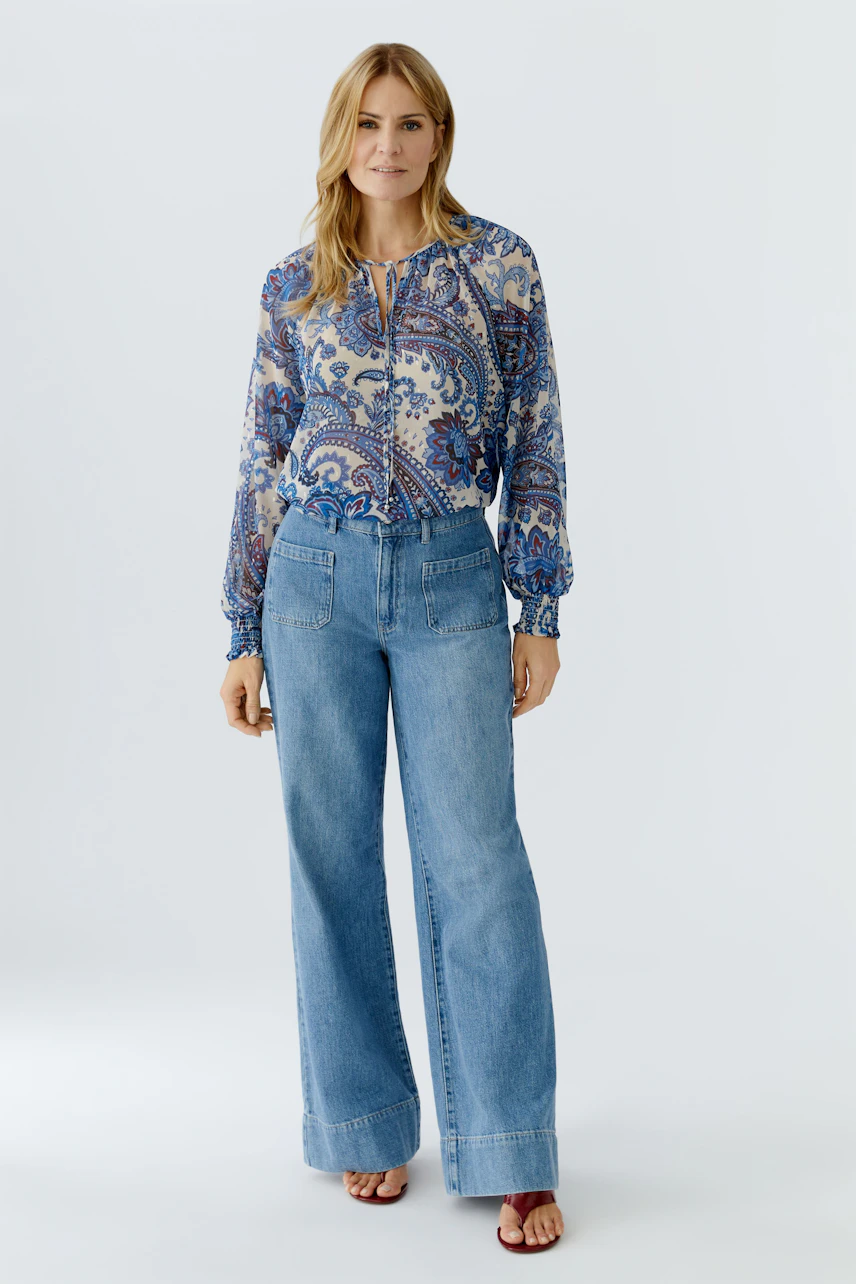 Casual women's blouse: Woman in a colorful patterned blouse with relaxed fit and balloon sleeves.