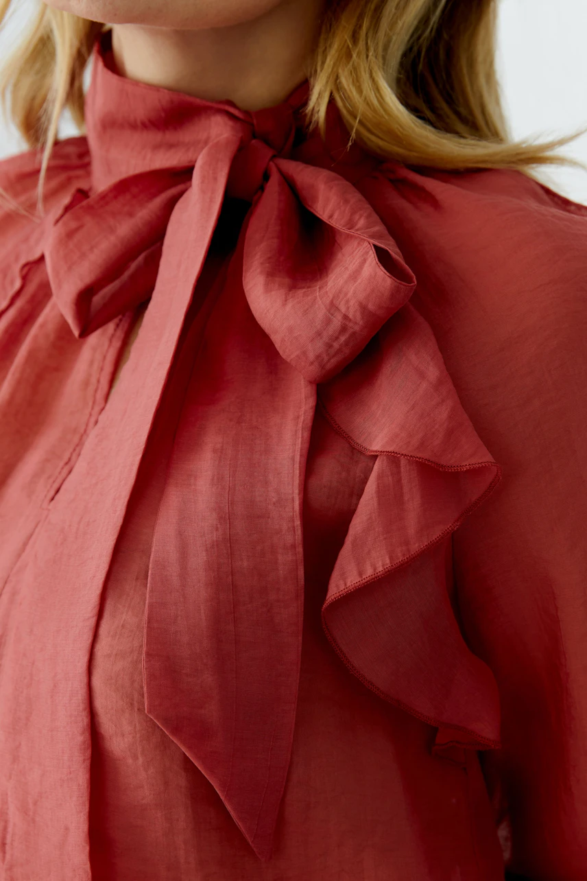 Damen-Bluse in Rot mit Schleifenkragen und Rüschendetails, lässig und modern.