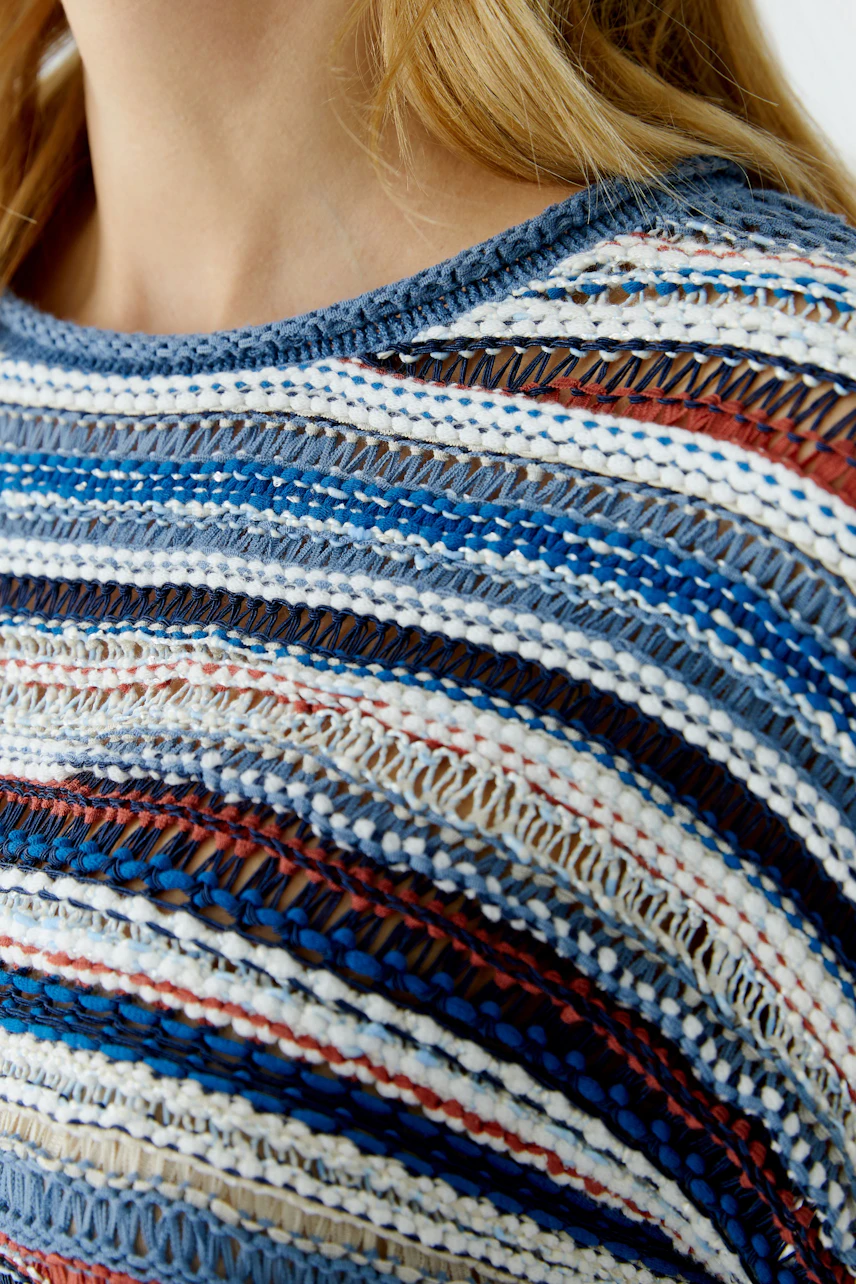 Casual women's pullover: Close-up of a woman in a colorful striped pullover with a relaxed fit.