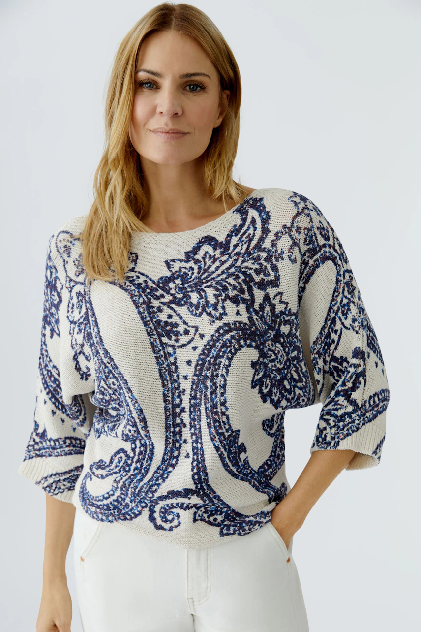 Damen-Pullover: Frau in beigem Pullover mit blauem Muster, lässig und modern.
