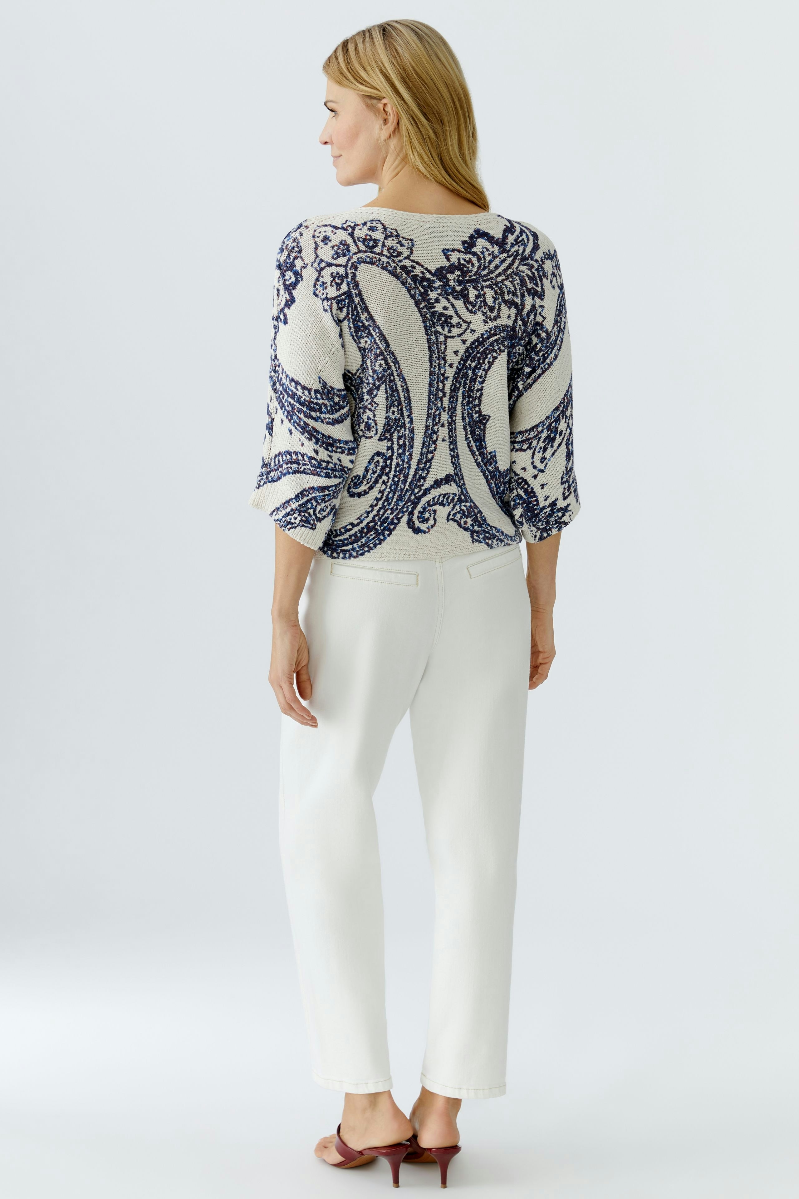 Casual women's pullover: A woman in a patterned pullover with three-quarter sleeves and white pants.
