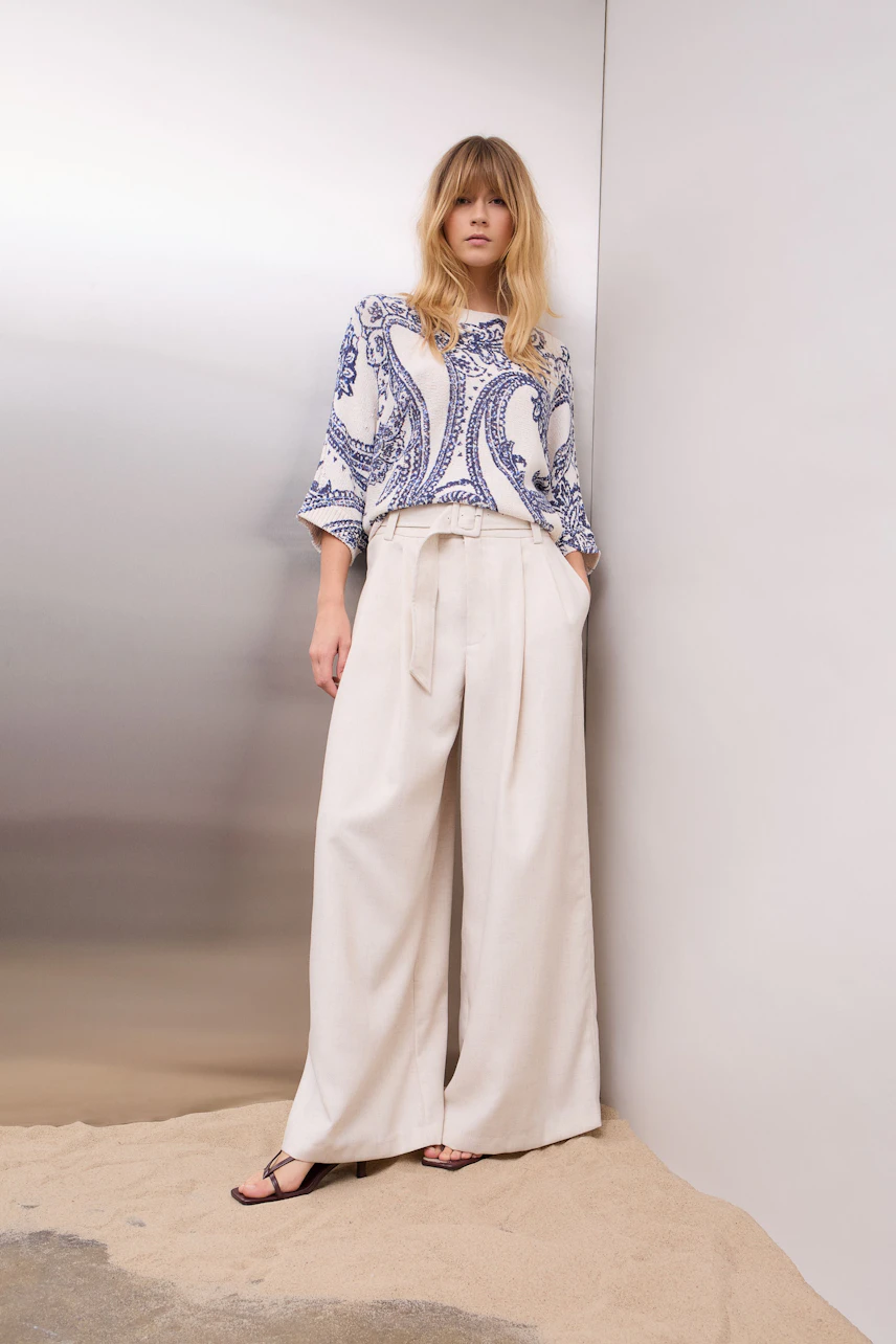 Damen-Pullover: Junge Frau in einem lässigen, gemusterten Pullover mit weitem Schnitt und hellen Hosen.