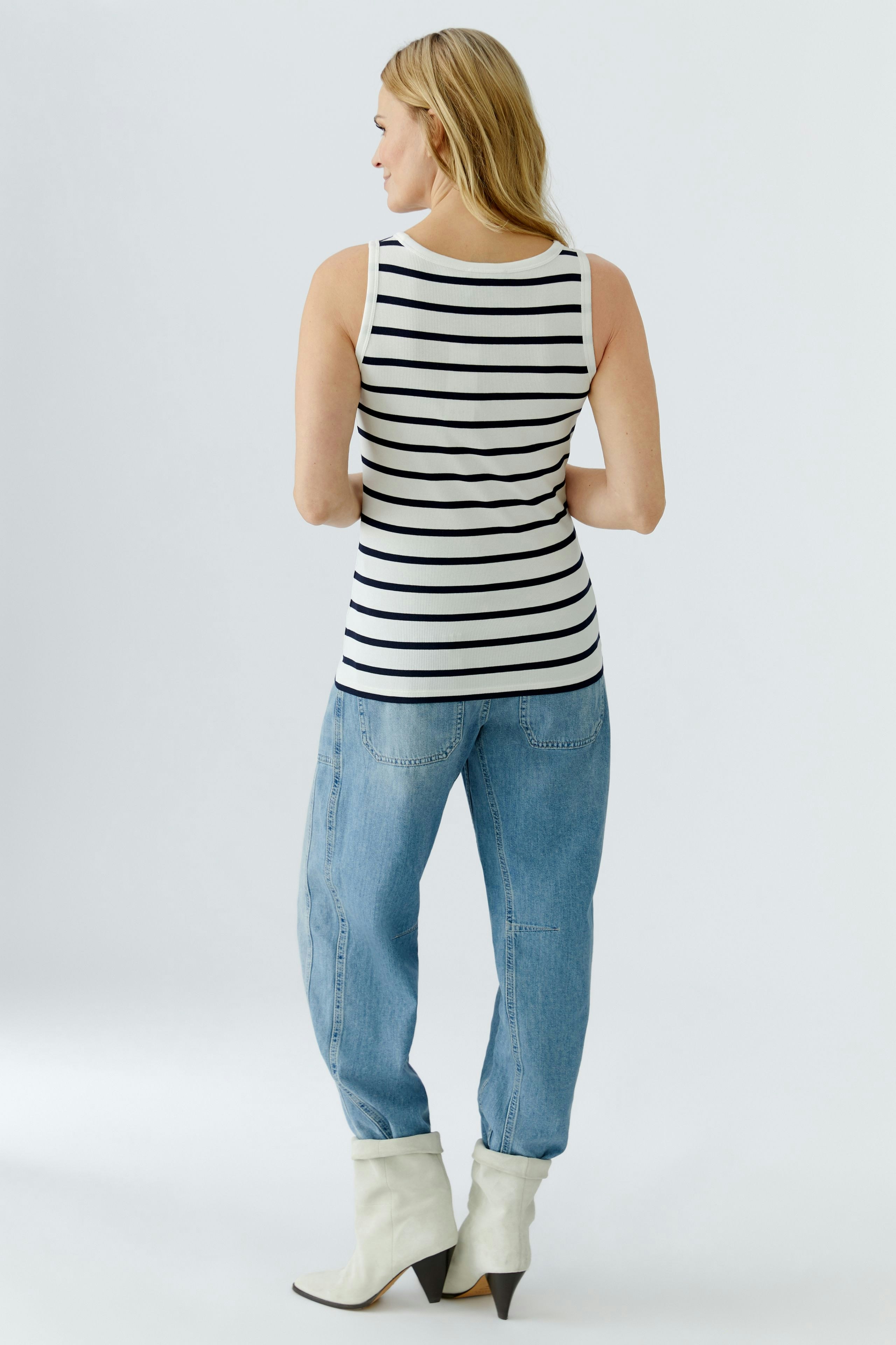 Casual women's tank top: A woman in a striped tank top paired with relaxed jeans.