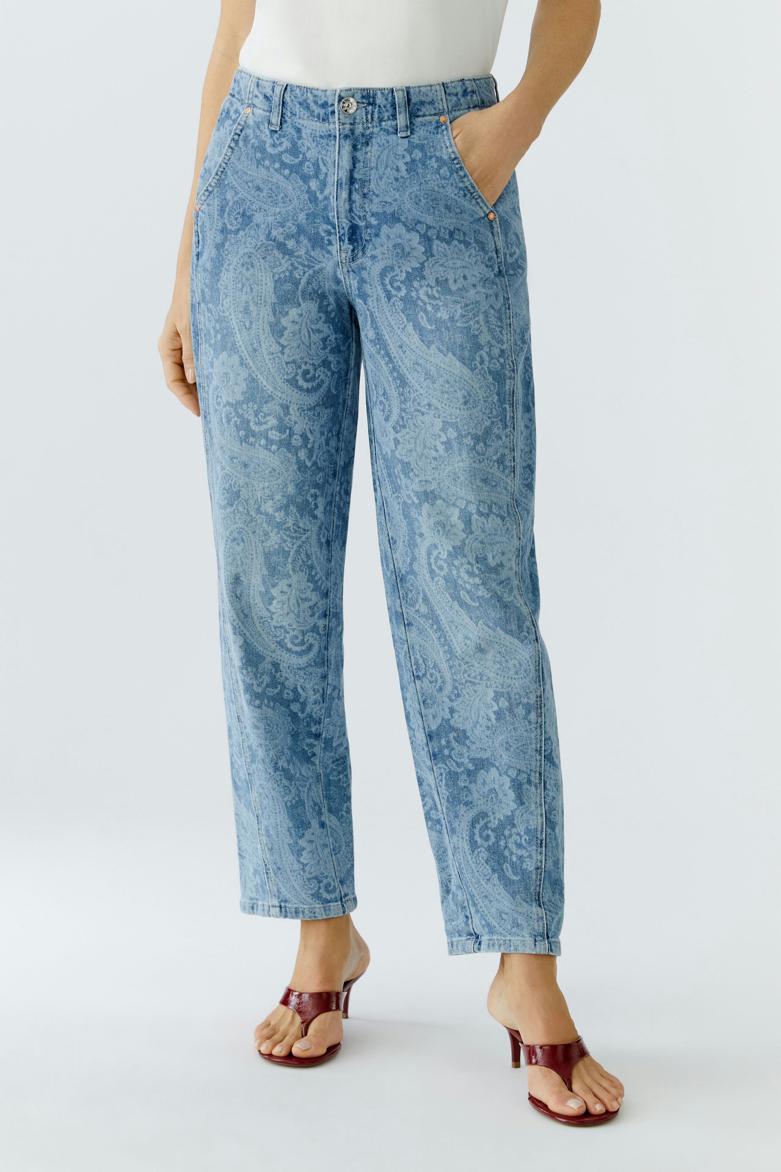 Bequeme Damen-Jeans: Frau in lässigen, hellblauen Relaxed Jeans mit Paisleymuster und Sandalen.