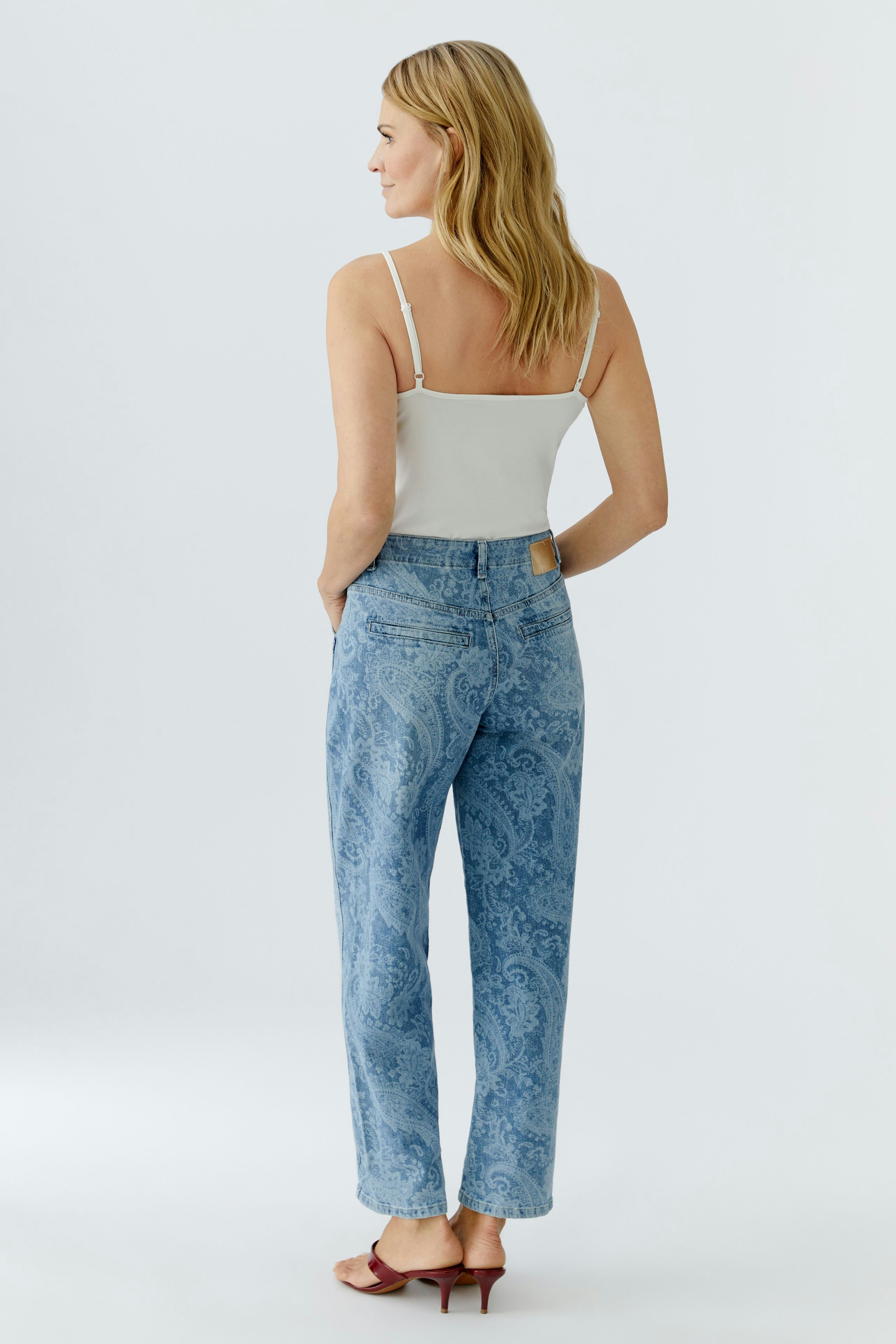 Bequeme Jeans Relaxed: Frau mit blonden Haaren trägt lässige, hellblaue Jeans mit Paisleymuster.