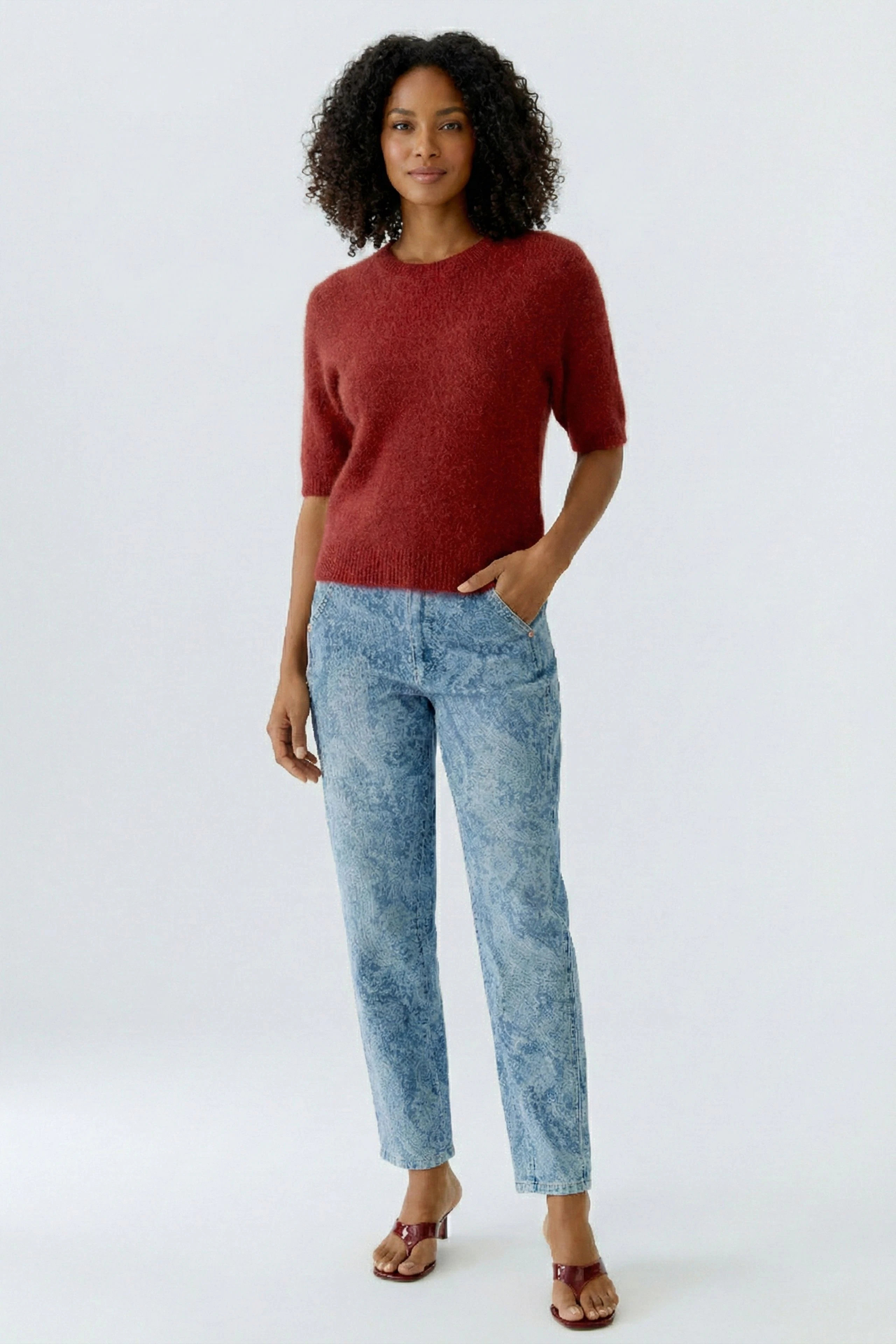 Bequeme Jeans Relaxed: Frau in lässigen Jeans mit Paisleymuster und rotem Pullover.