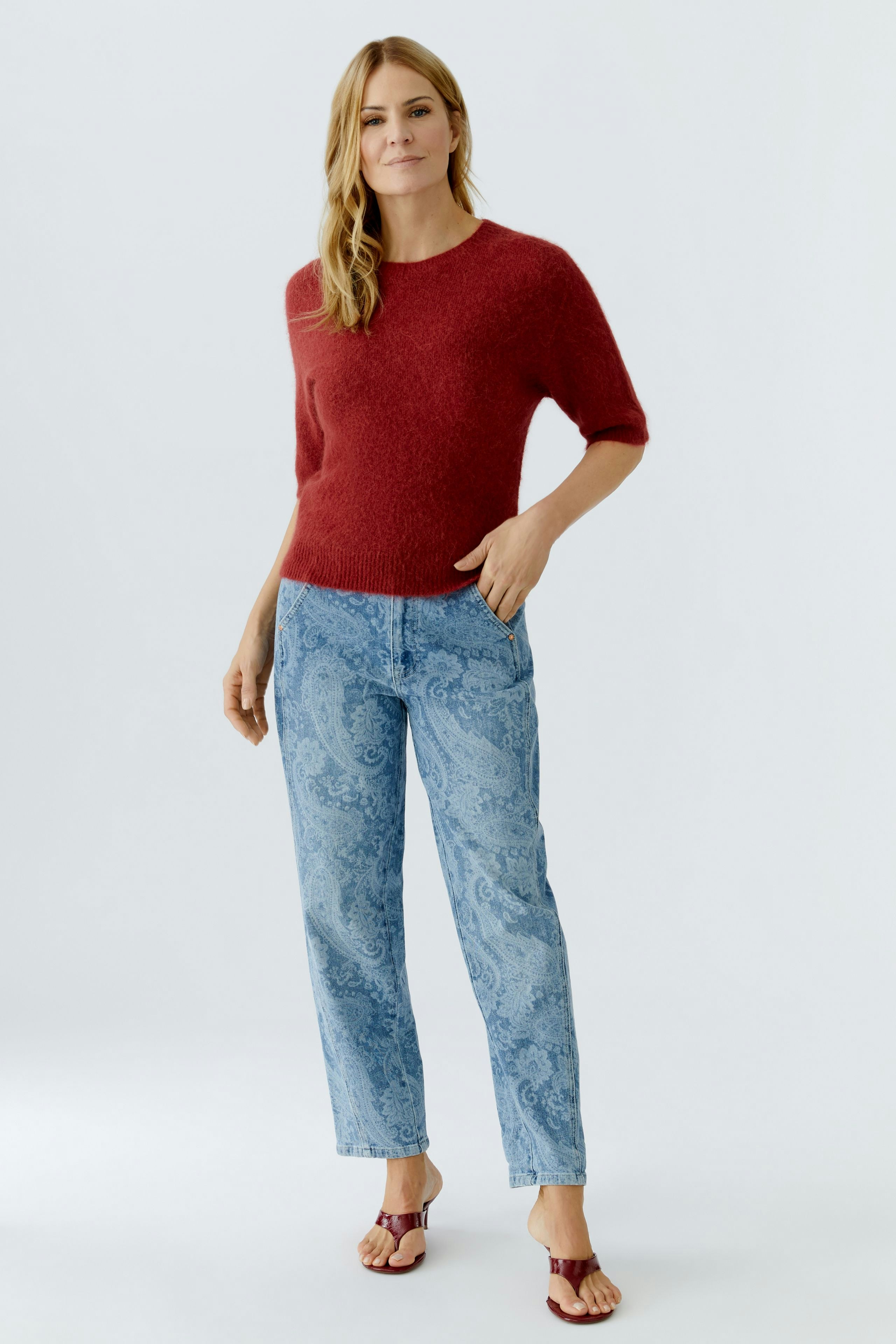 Bequeme Jeans Relaxed: Frau in lässigen Jeans mit Paisleymuster und rotem Pullover.